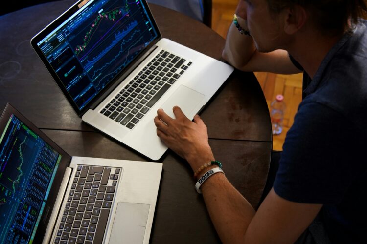 A person analyzing marketing data on two laptop screens, displaying graphs and charts.