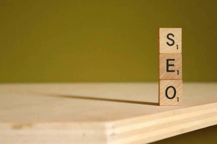 Wooden Scrabble tiles stacked to spell "SEO" on a wooden surface