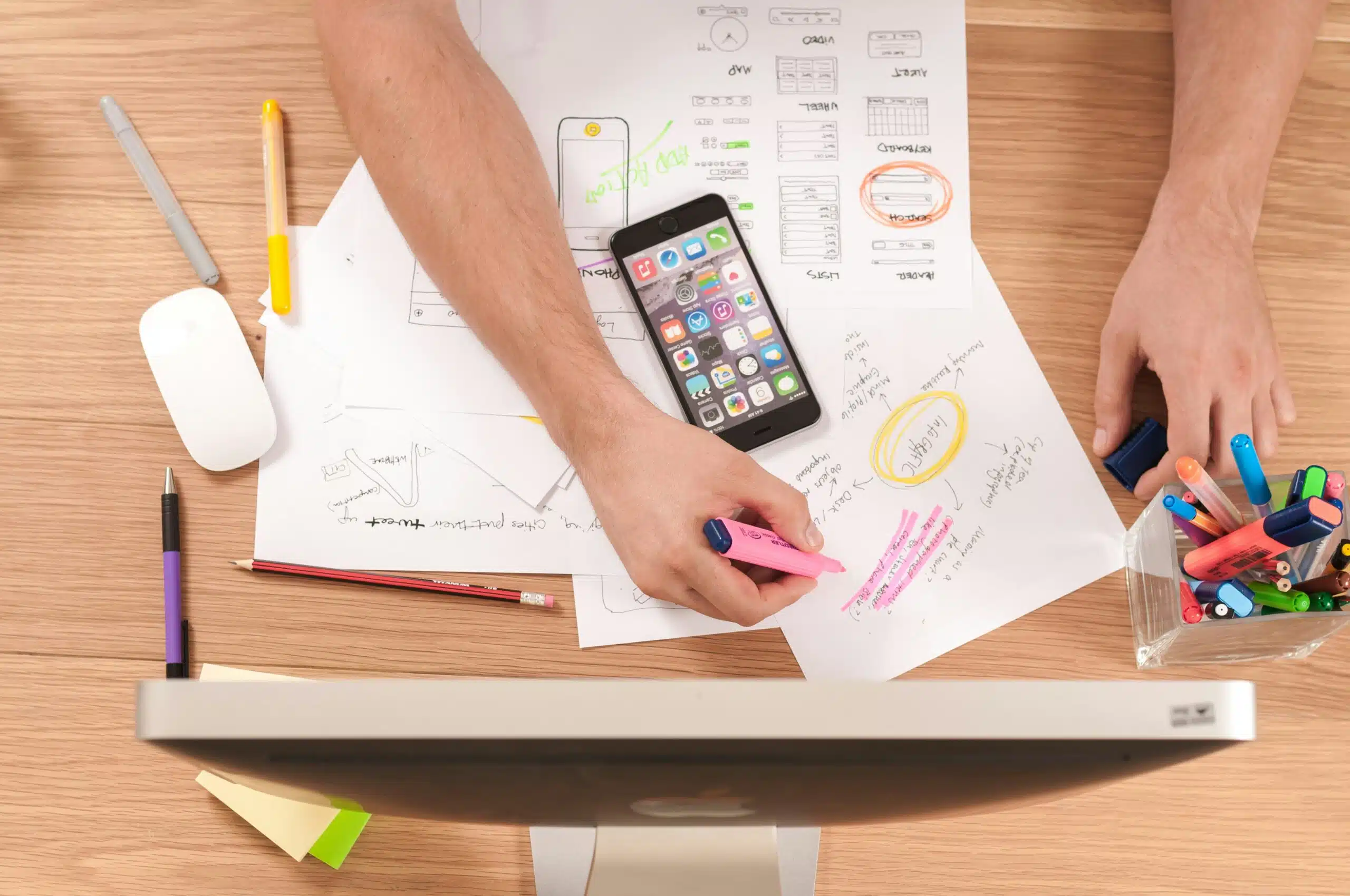  A marketer brainstorming AI-driven insights with handwritten notes, charts, and a smartphone on a desk.