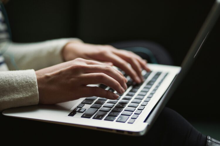 Close-up of hands typing on a laptop keyboard, illustrating AI writing tool pricing evaluations.