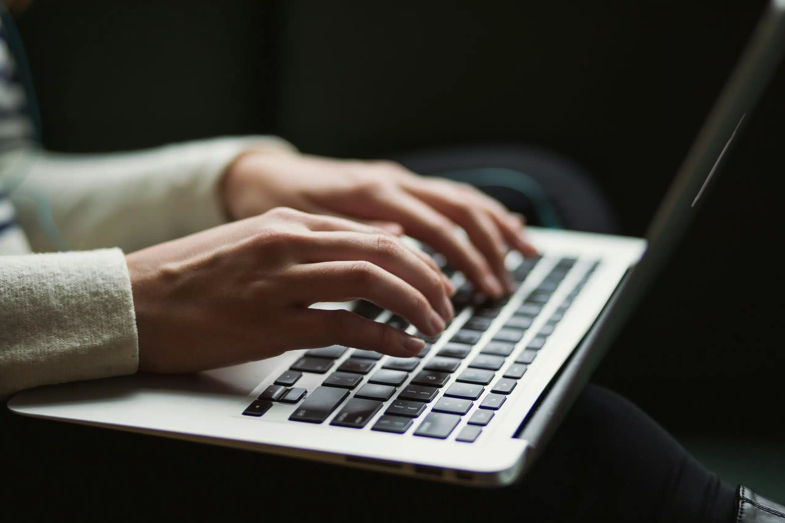 Close-up of hands typing on a laptop keyboard, illustrating AI content tool limitations.