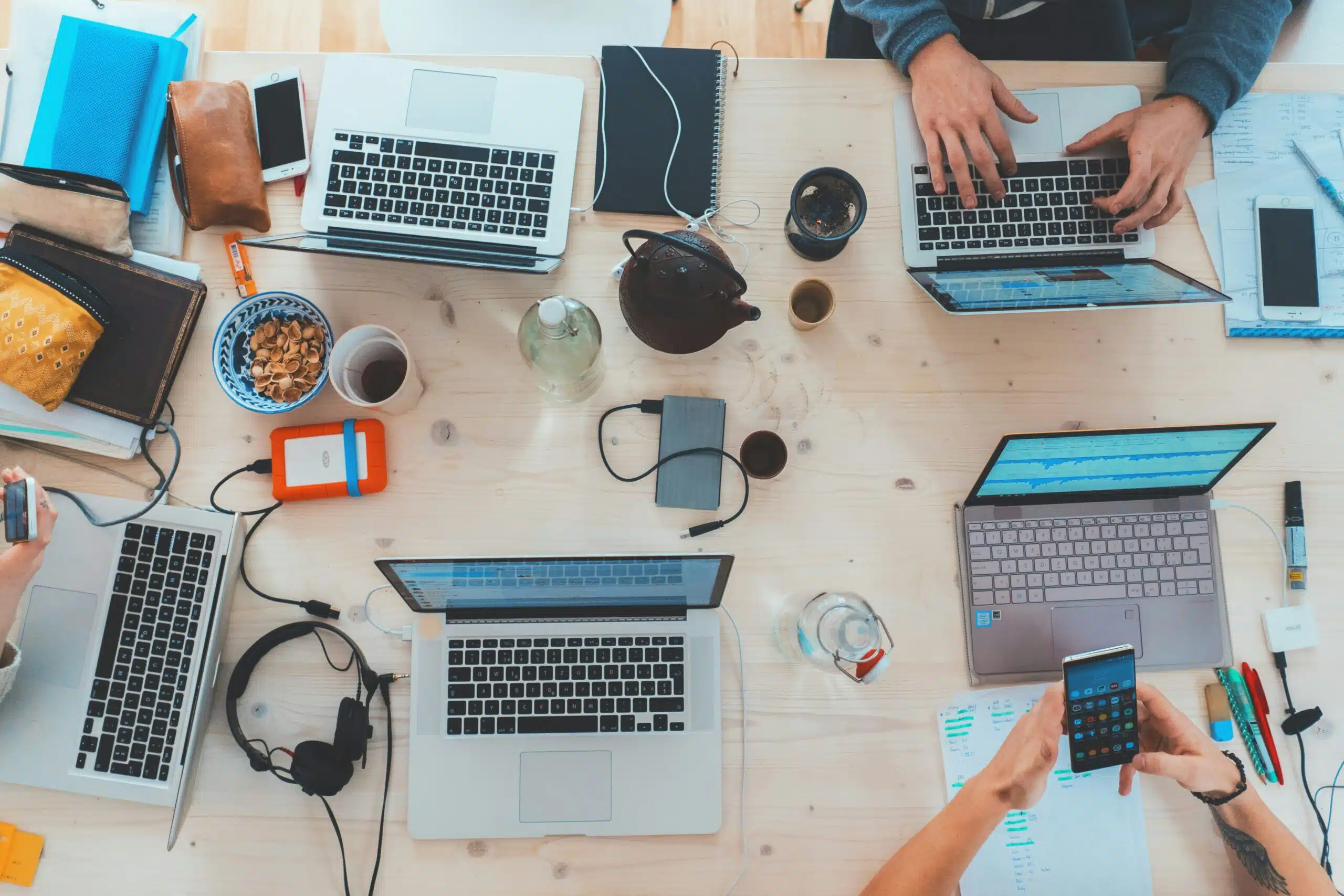 A collaborative workspace with laptops, notebooks, and mobile devices in use, illustrating the practical benefits of data-driven customer analysis for informed decision-making.