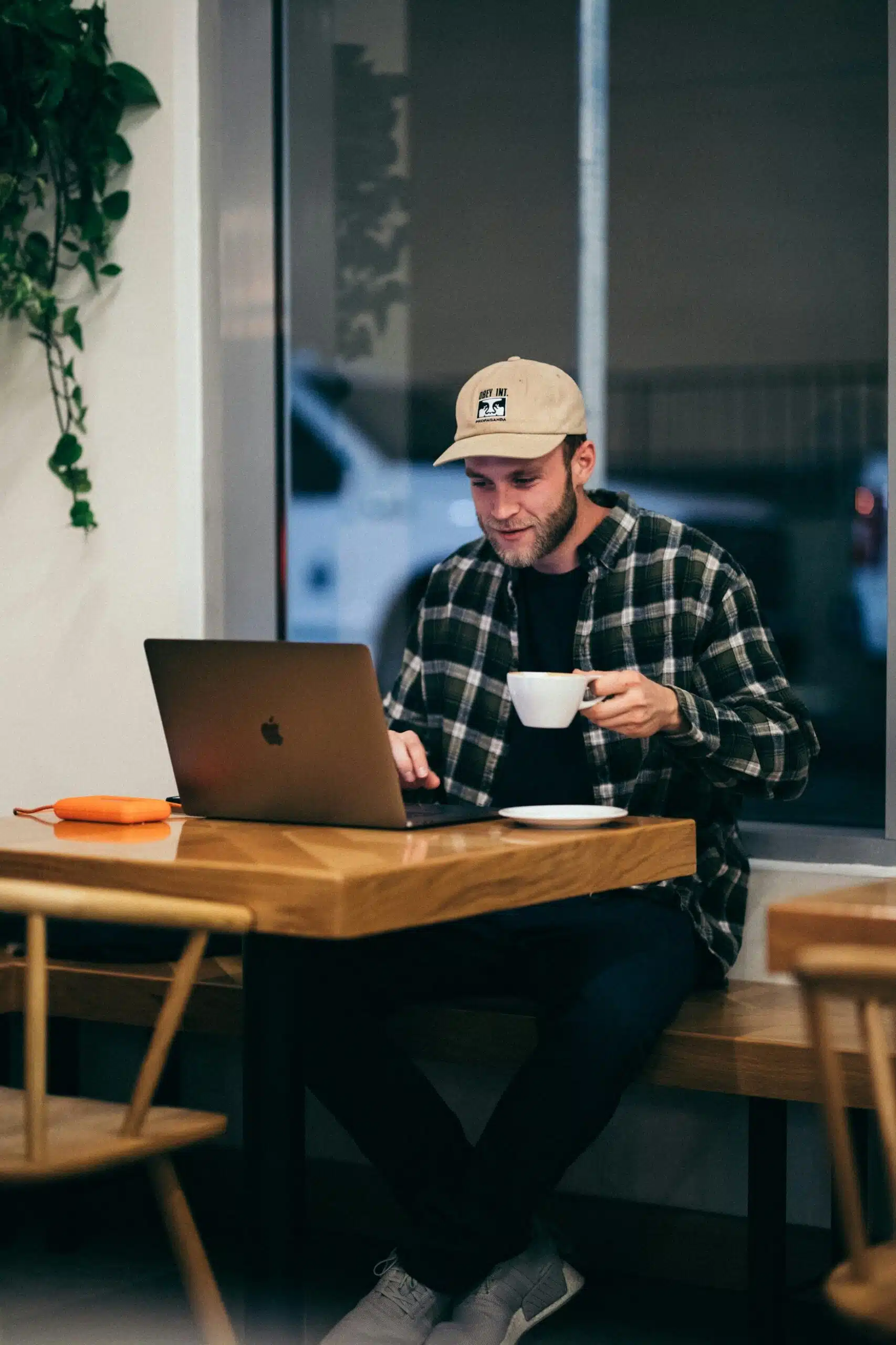 a man working on laptop in a cafe drinking coffee