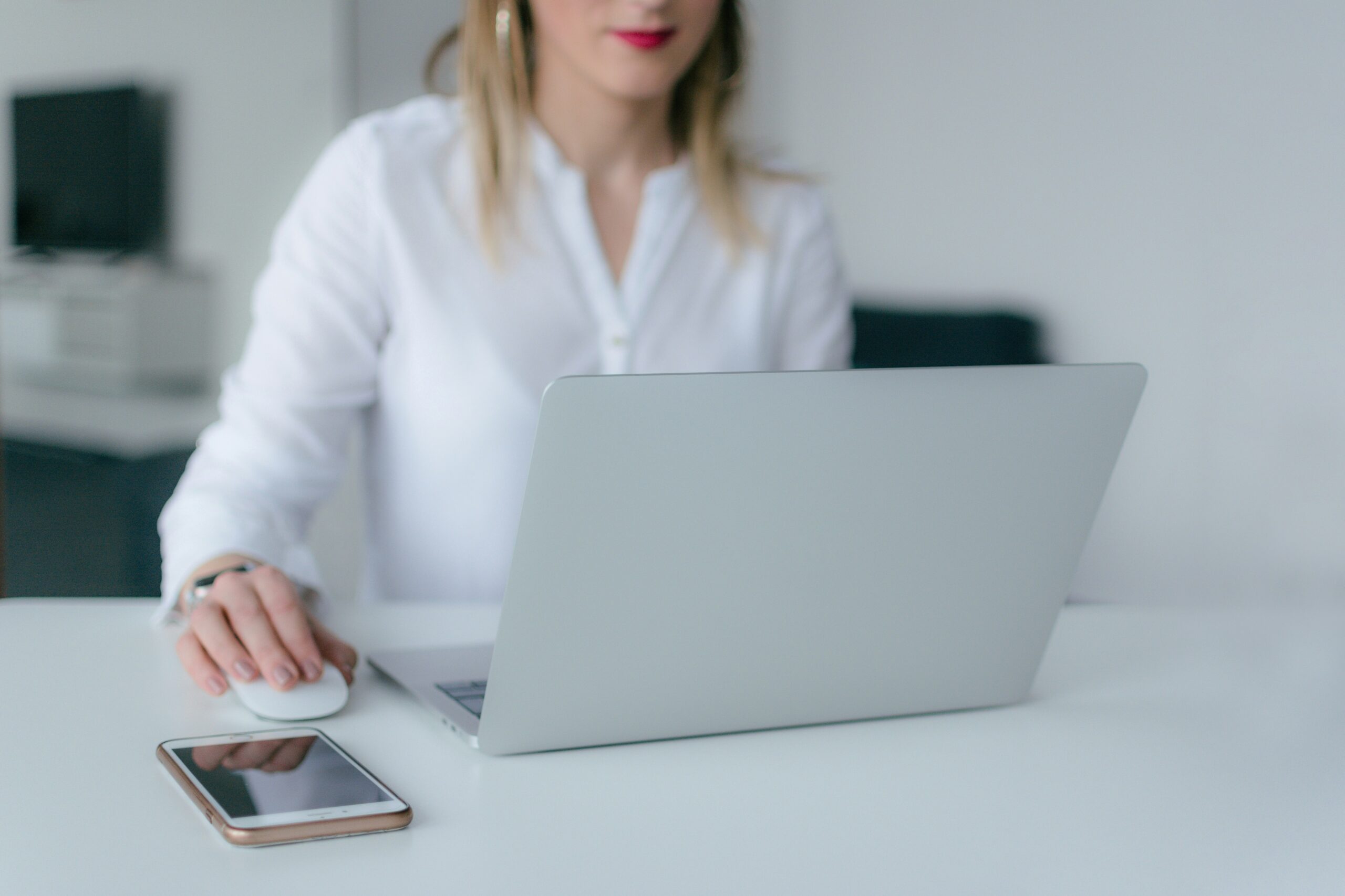 Professional using a laptop with a smartphone nearby