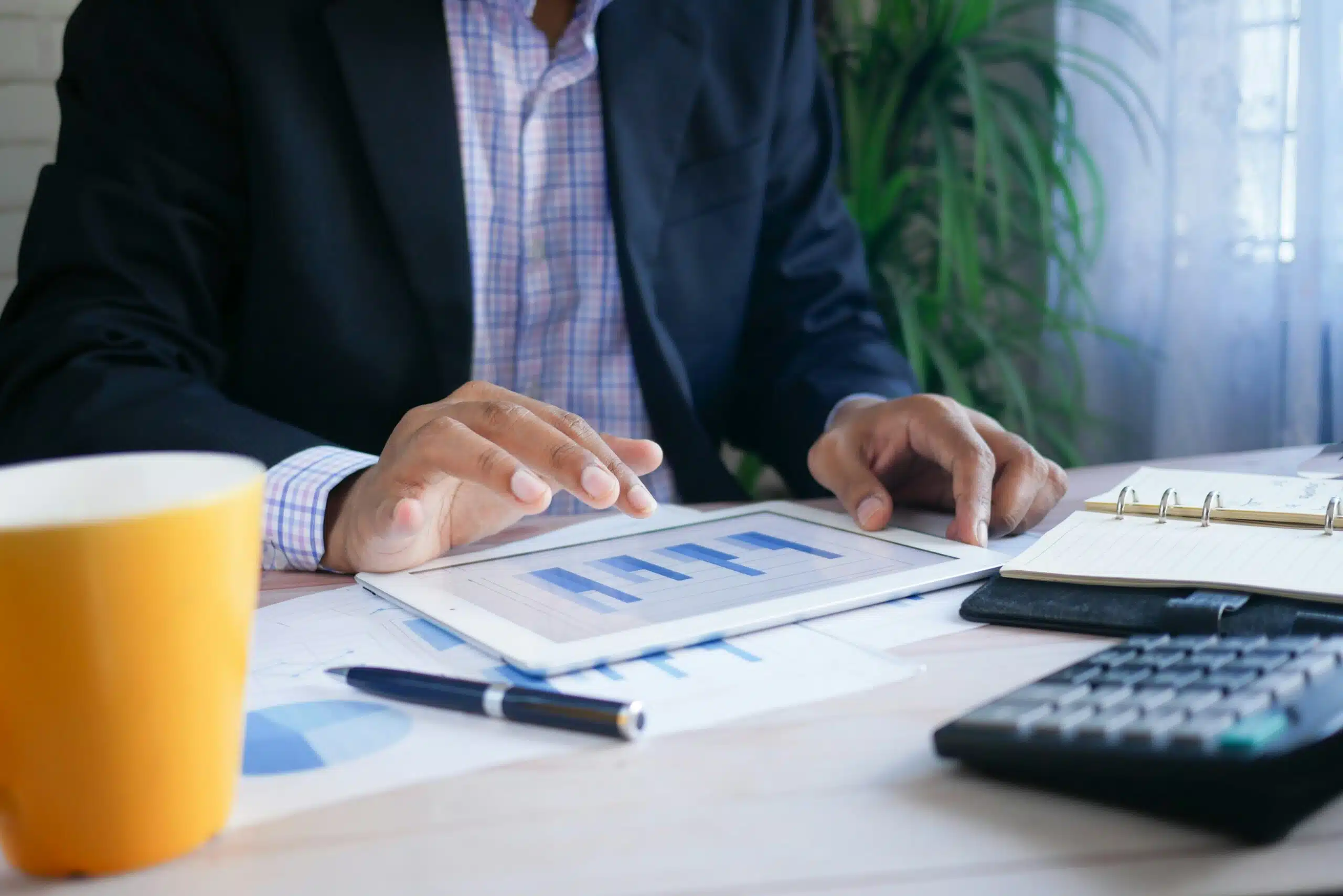  A professional reviewing bar charts on a tablet,