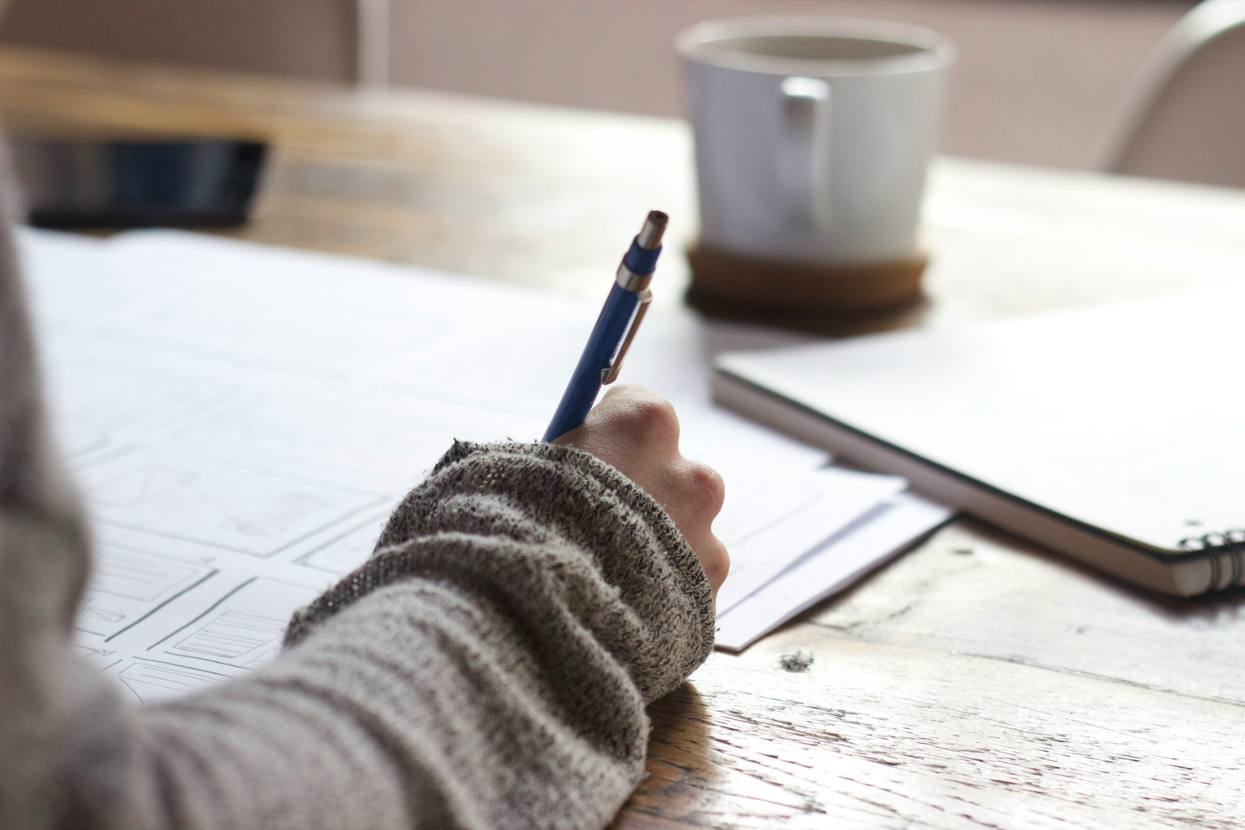 A person writing with a pen on a notebook 