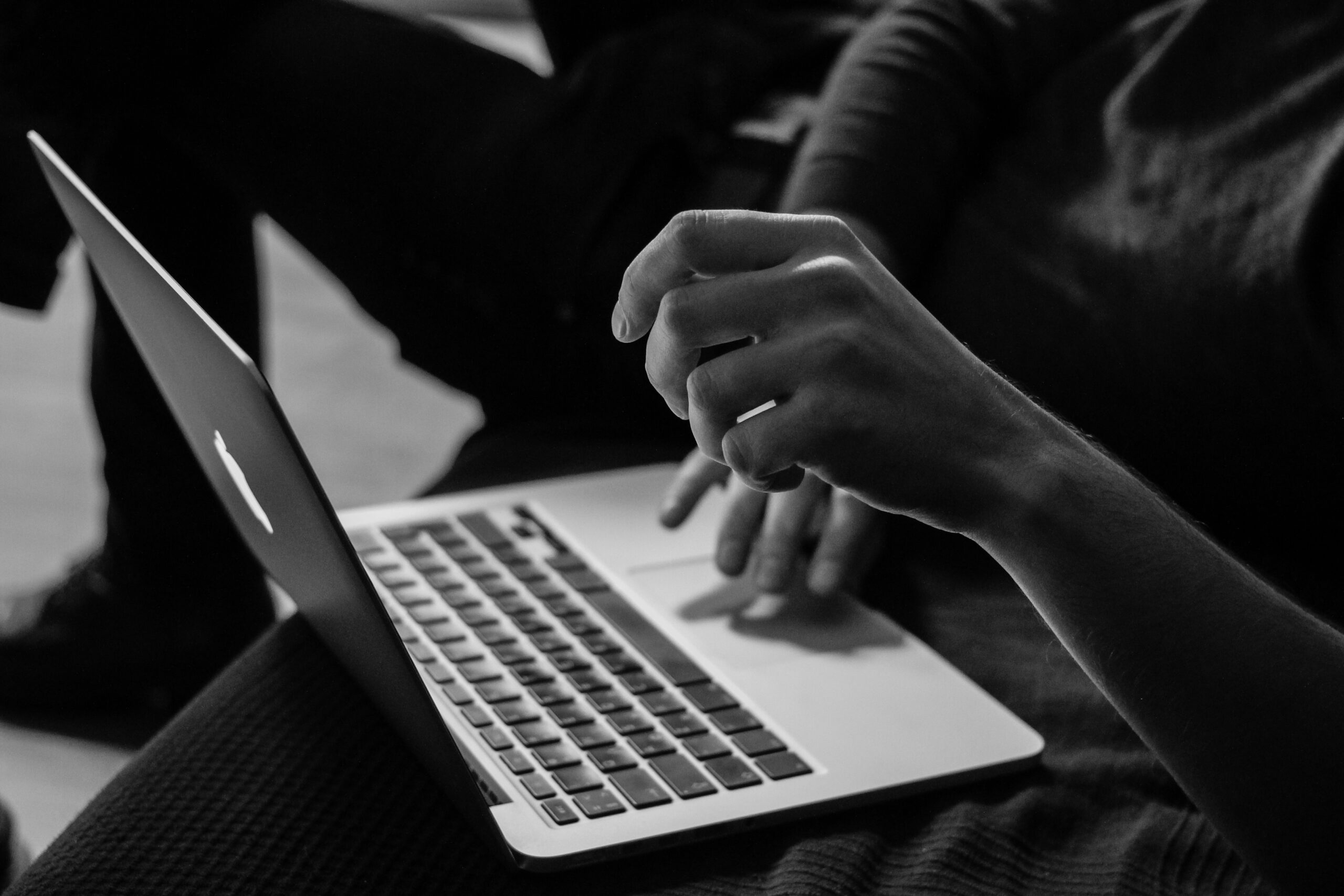 Black and white image of a person using a laptop, representing traditional copywriting methods.