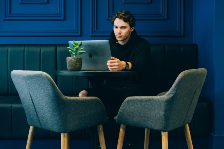 Man working on a laptop at a modern office with a dark blue wall