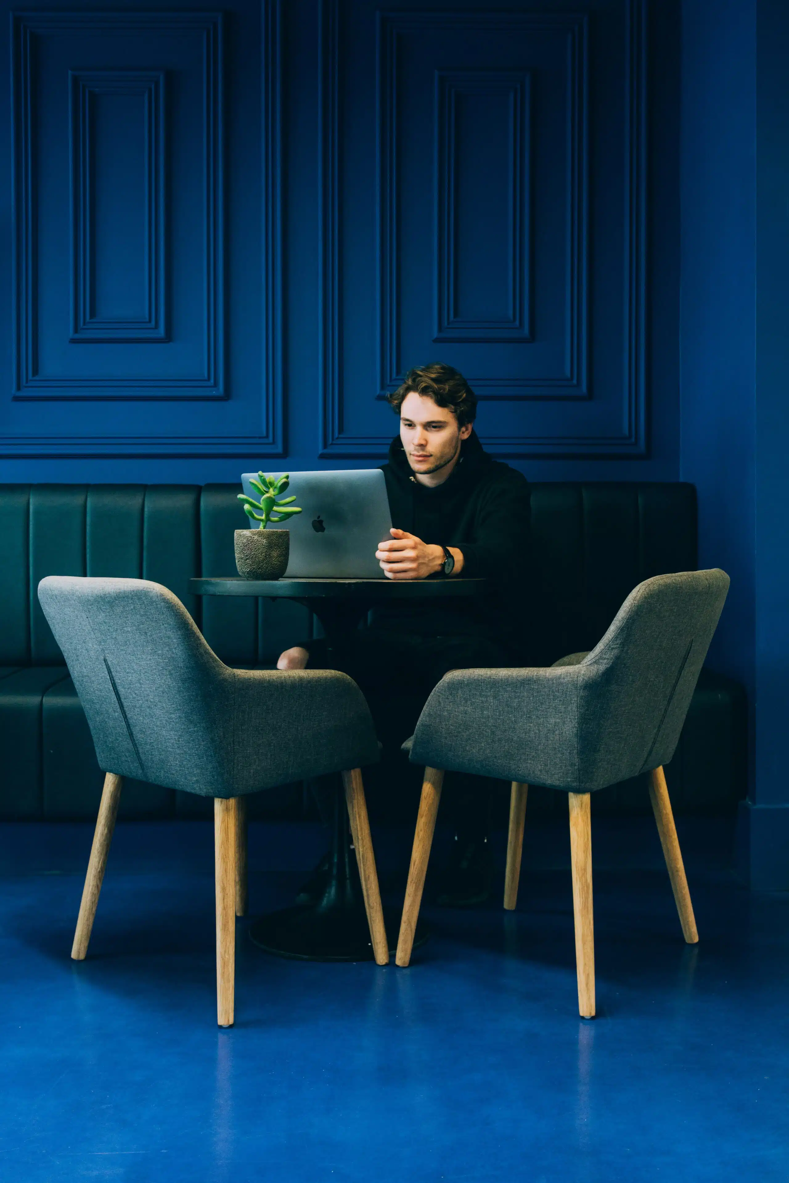 Man working on a laptop at a modern office with a dark blue wall