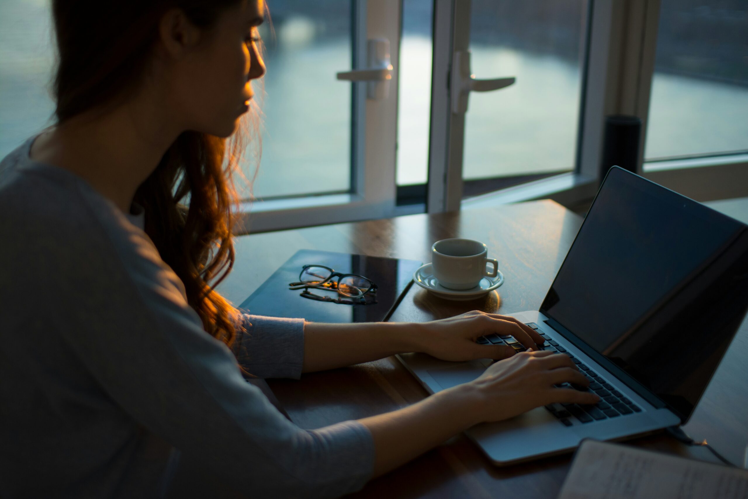 Woman working on a laptop by a window 