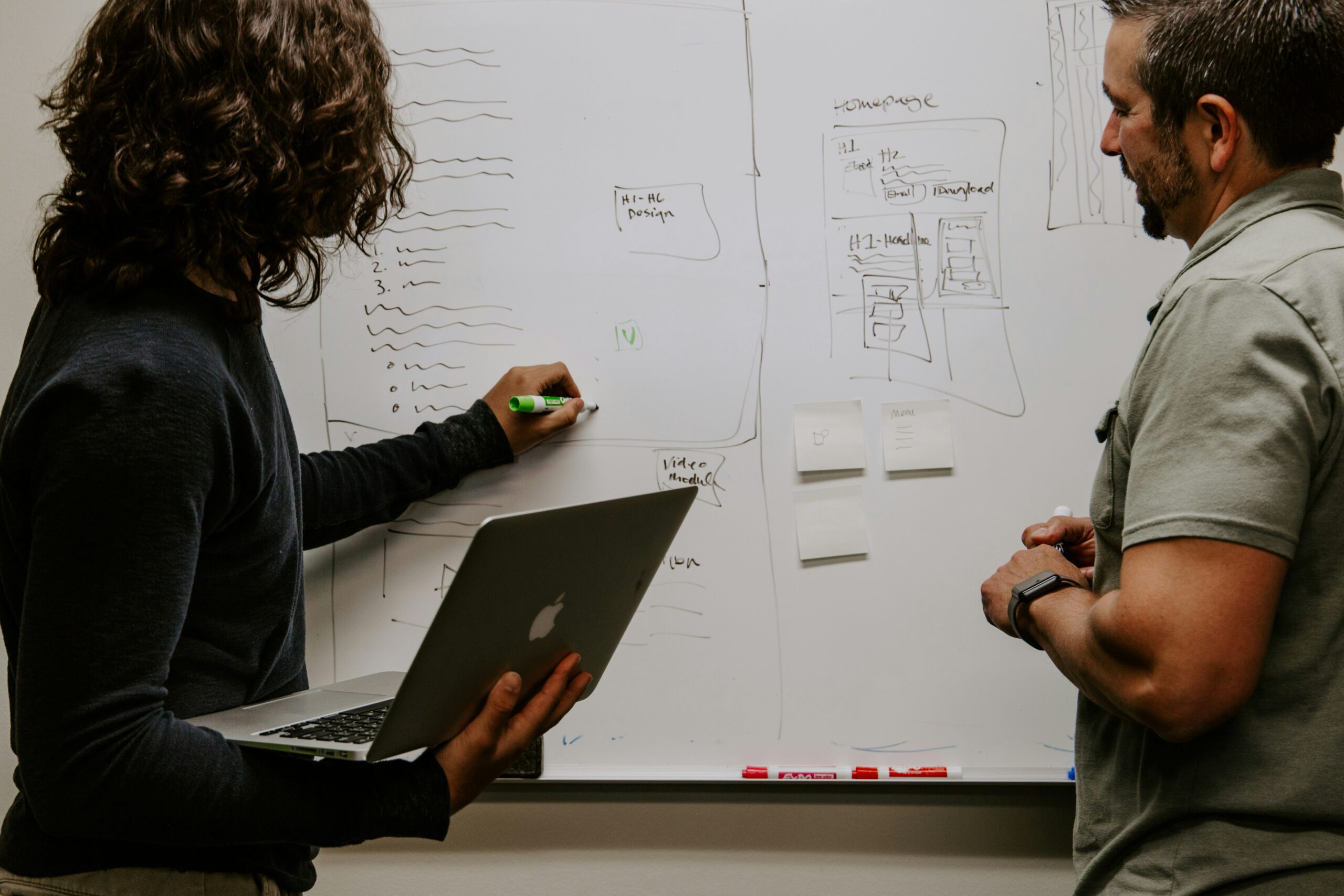 Two professionals discussing AI marketing strategies in front of a whiteboard 