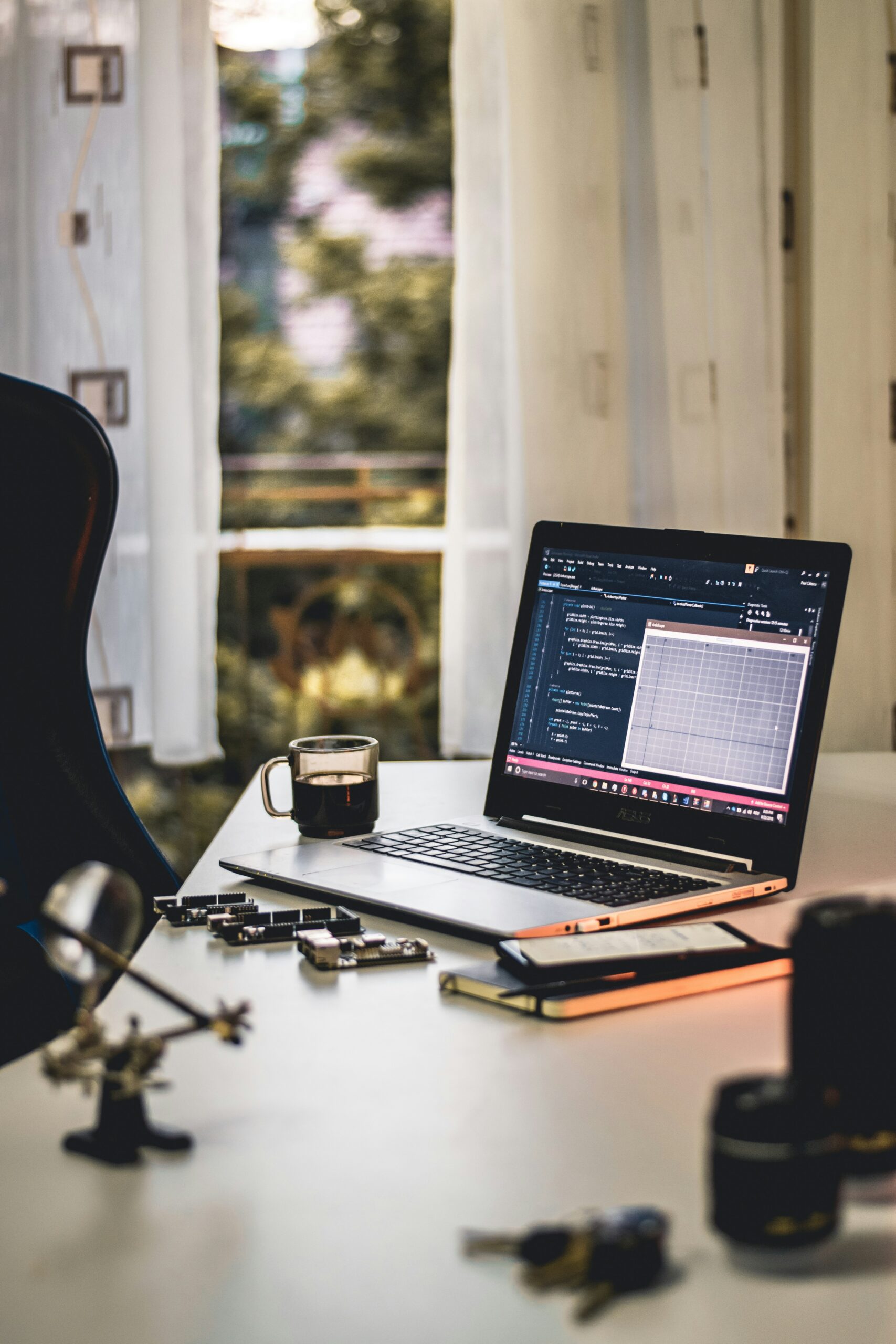 A laptop on a desk displaying analytics and a data graph, with a coffee cup