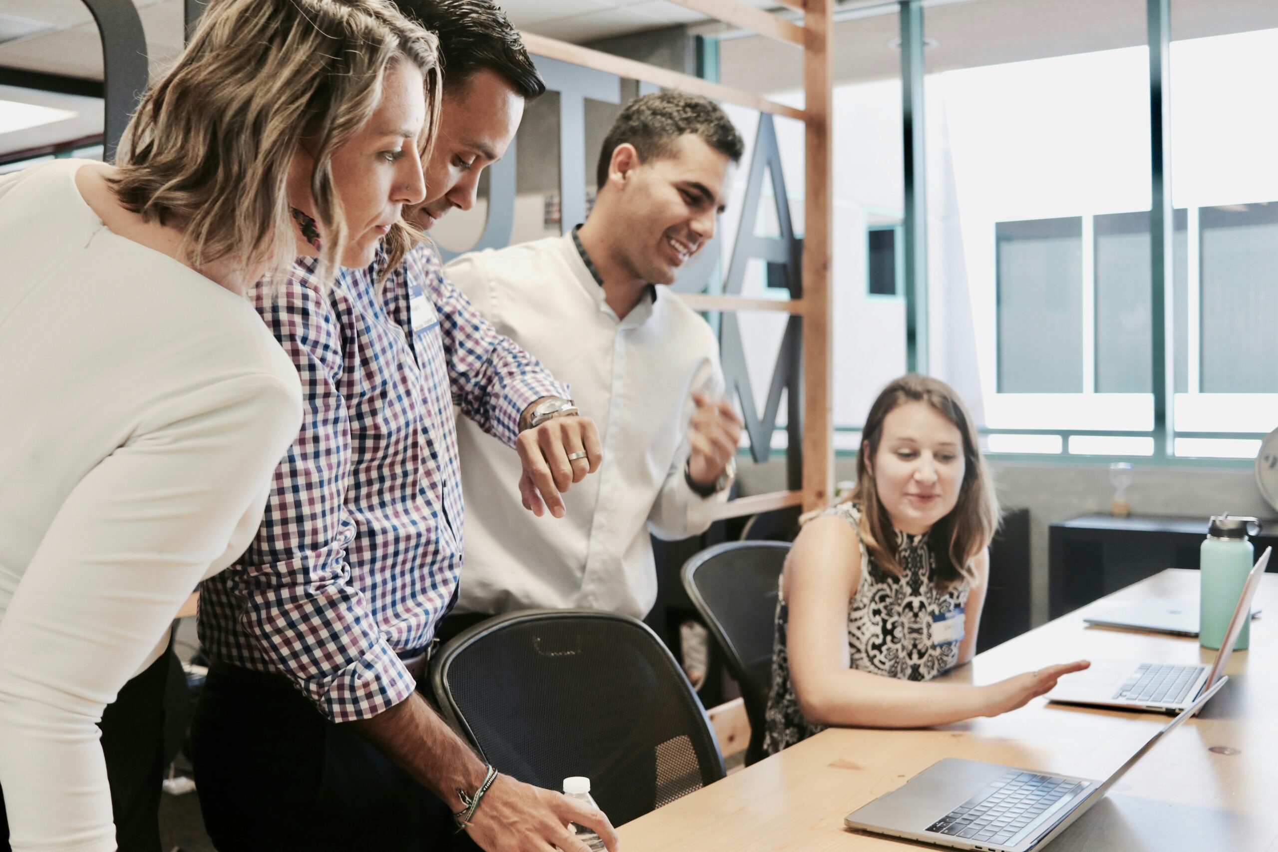 A diverse team enthusiastically discussing AI content solutions around a laptop.