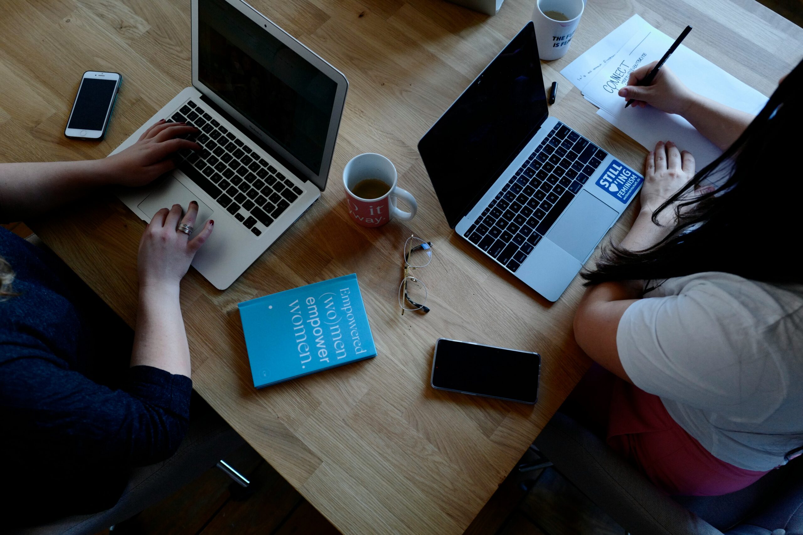 Three people working on laptops and taking notes at a wooden table, collaborating on local SEO tools.