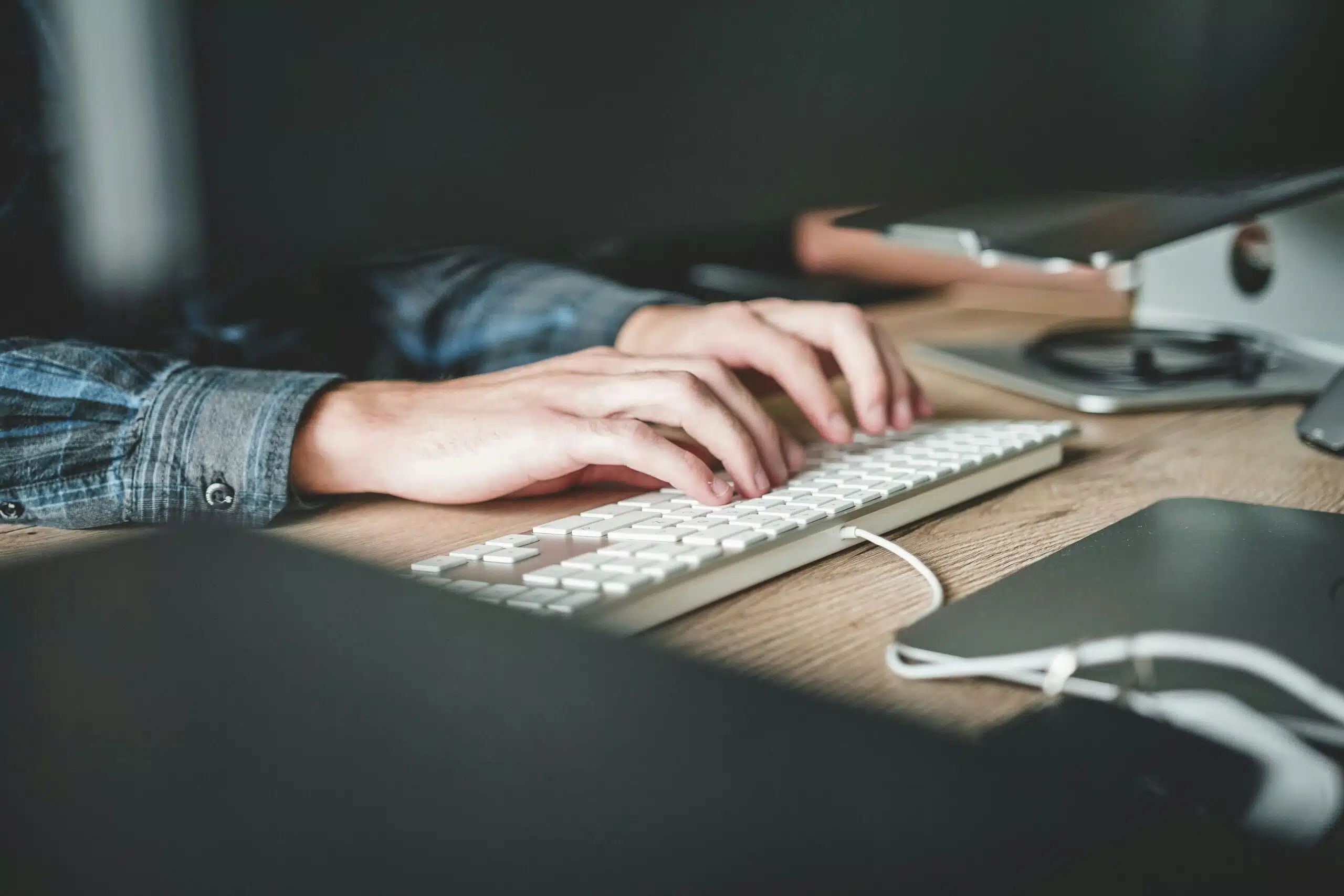 Hands typing on a white keyboard in an office setting