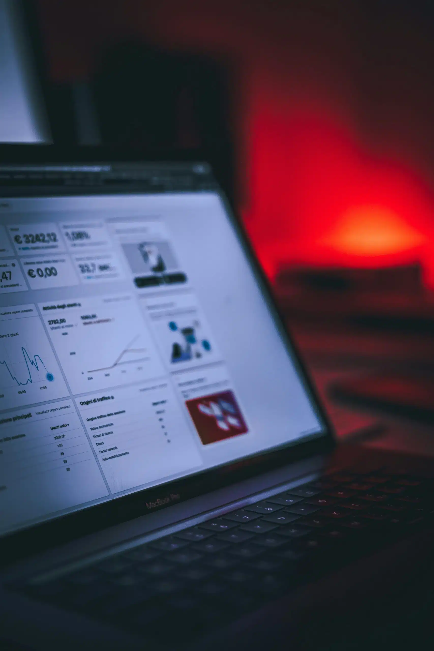 A laptop screen displaying SEO analytics in a dimly lit room with red lighting.