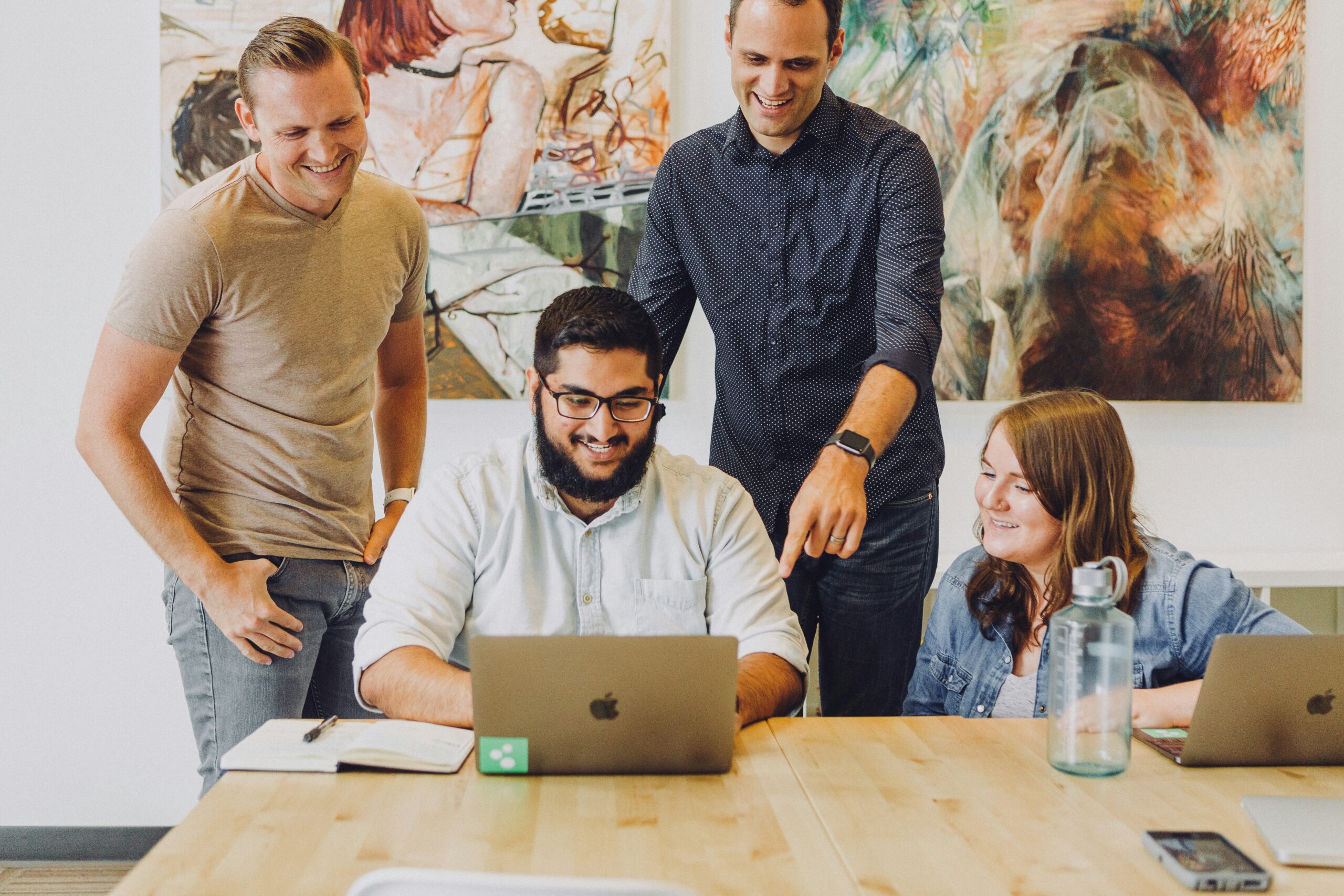 four people looking at a laptop and discussing The Future of Customer Feedback