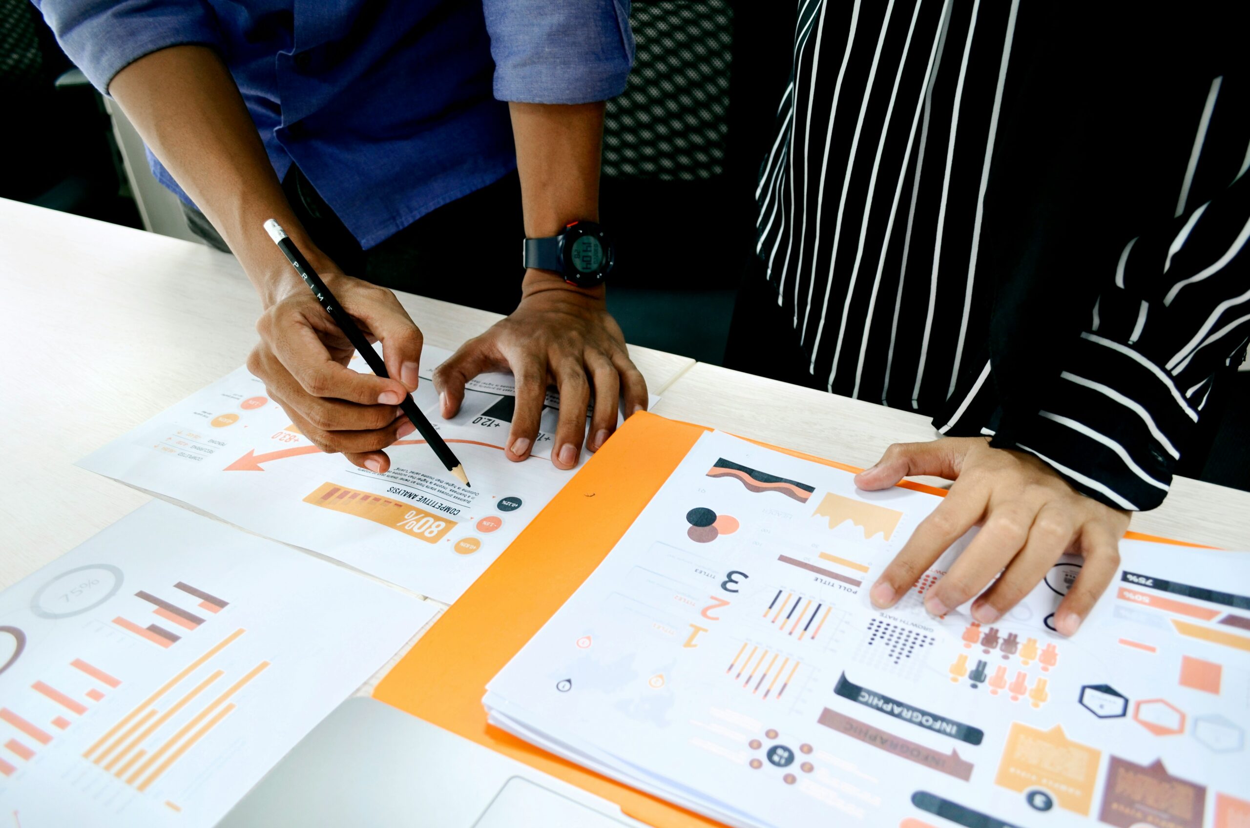 Two marketers reviewing data visualization charts printed on paper