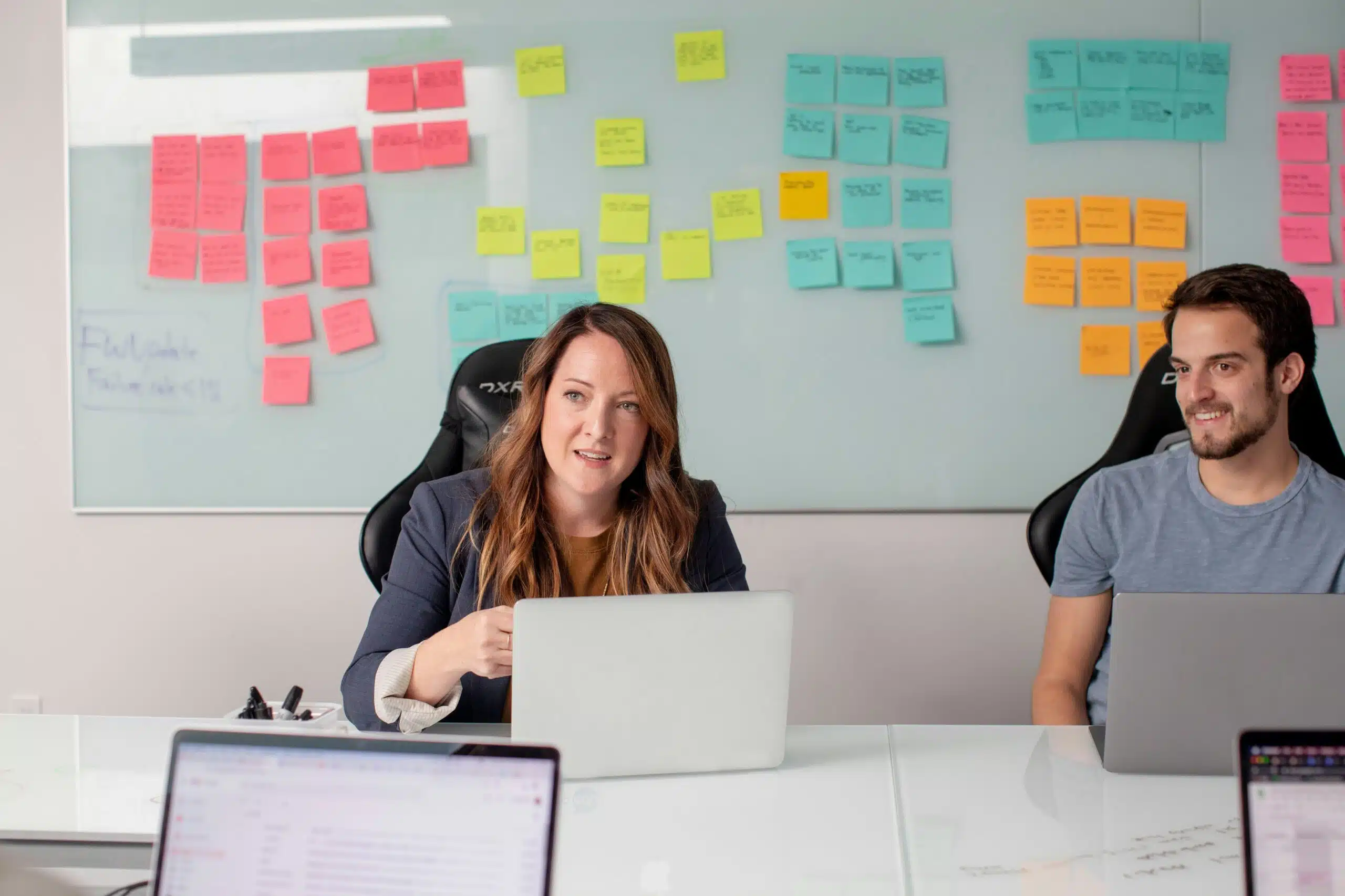 Two professionals in a meeting with sticky notes on a whiteboard
