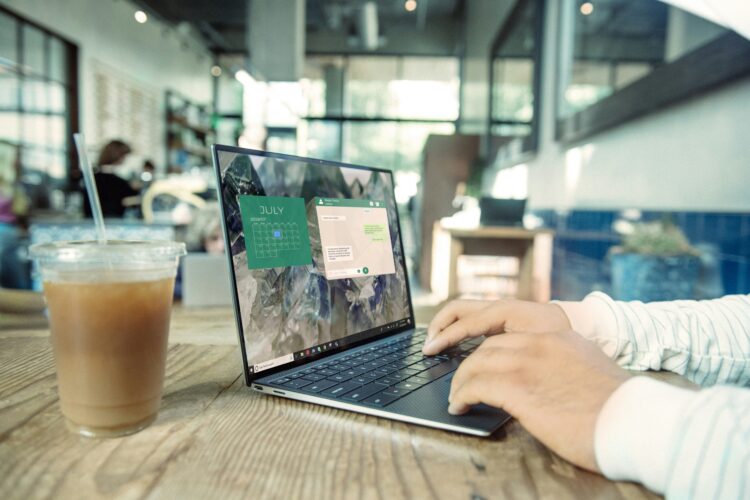 Person typing on a laptop in a café, with a calendar and messaging app open on the screen