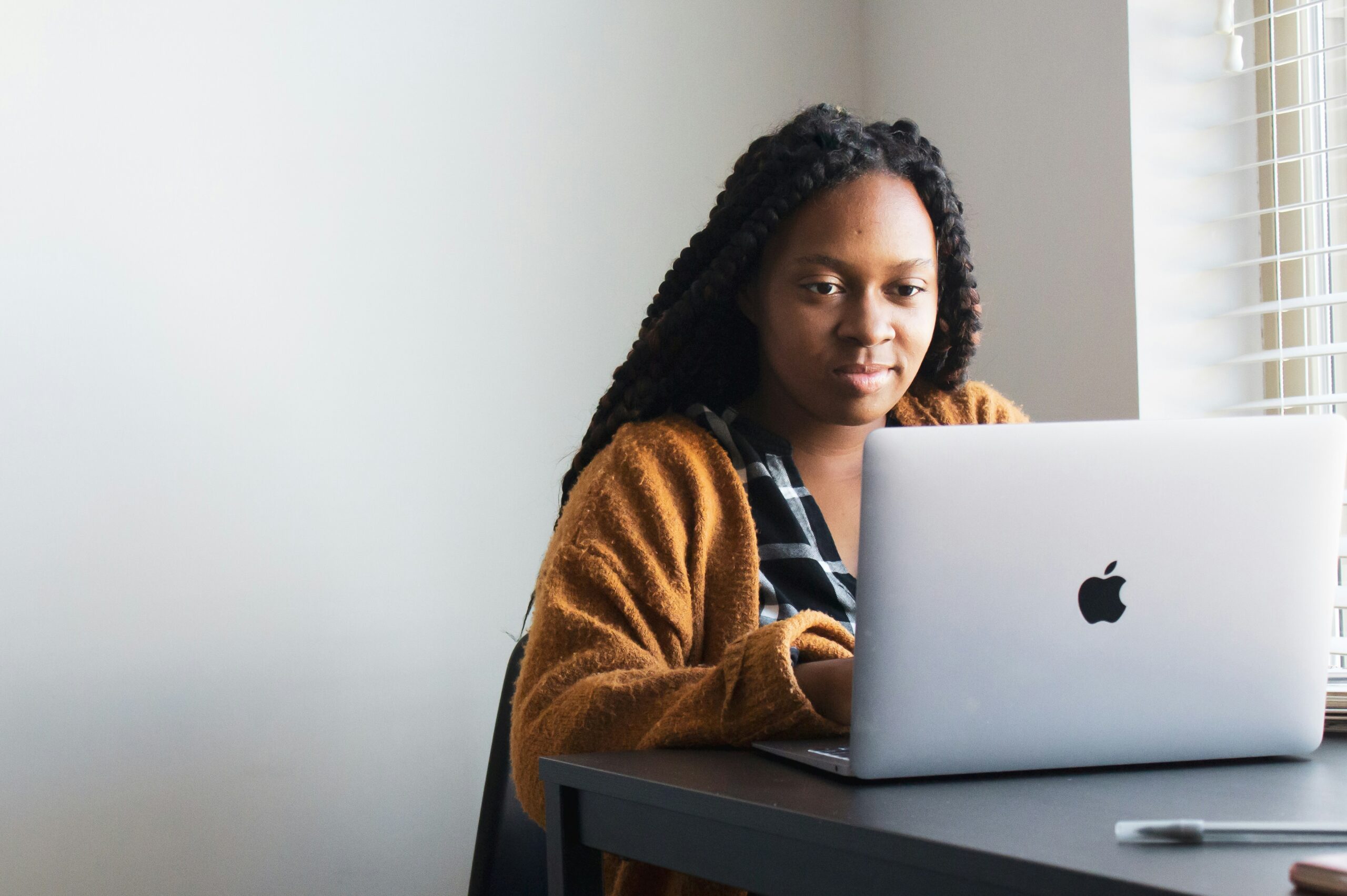 Woman working on a MacBook near a window, symbolizing challenges and limitations of AI writing tools.