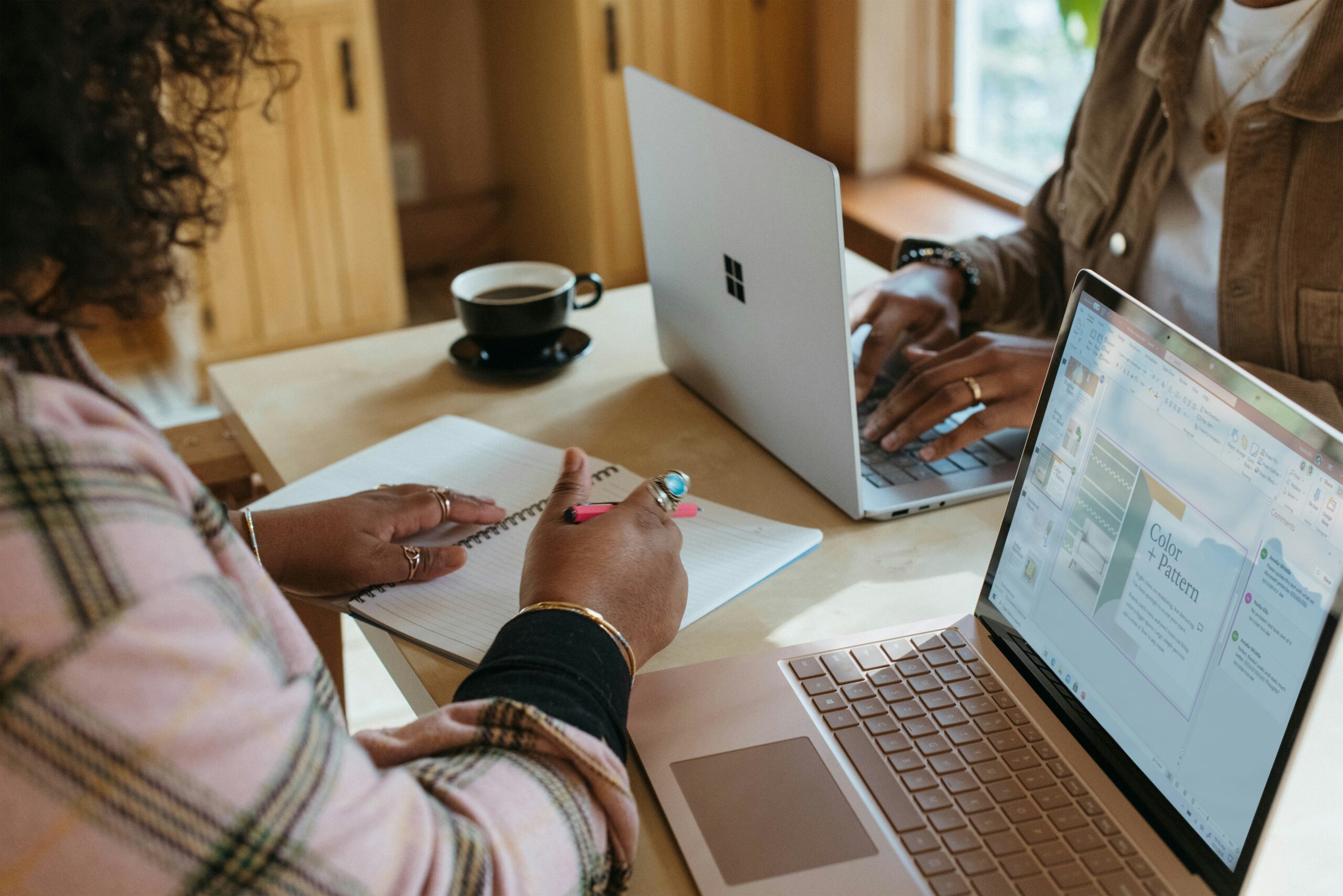 Two people collaborating at a table with laptops