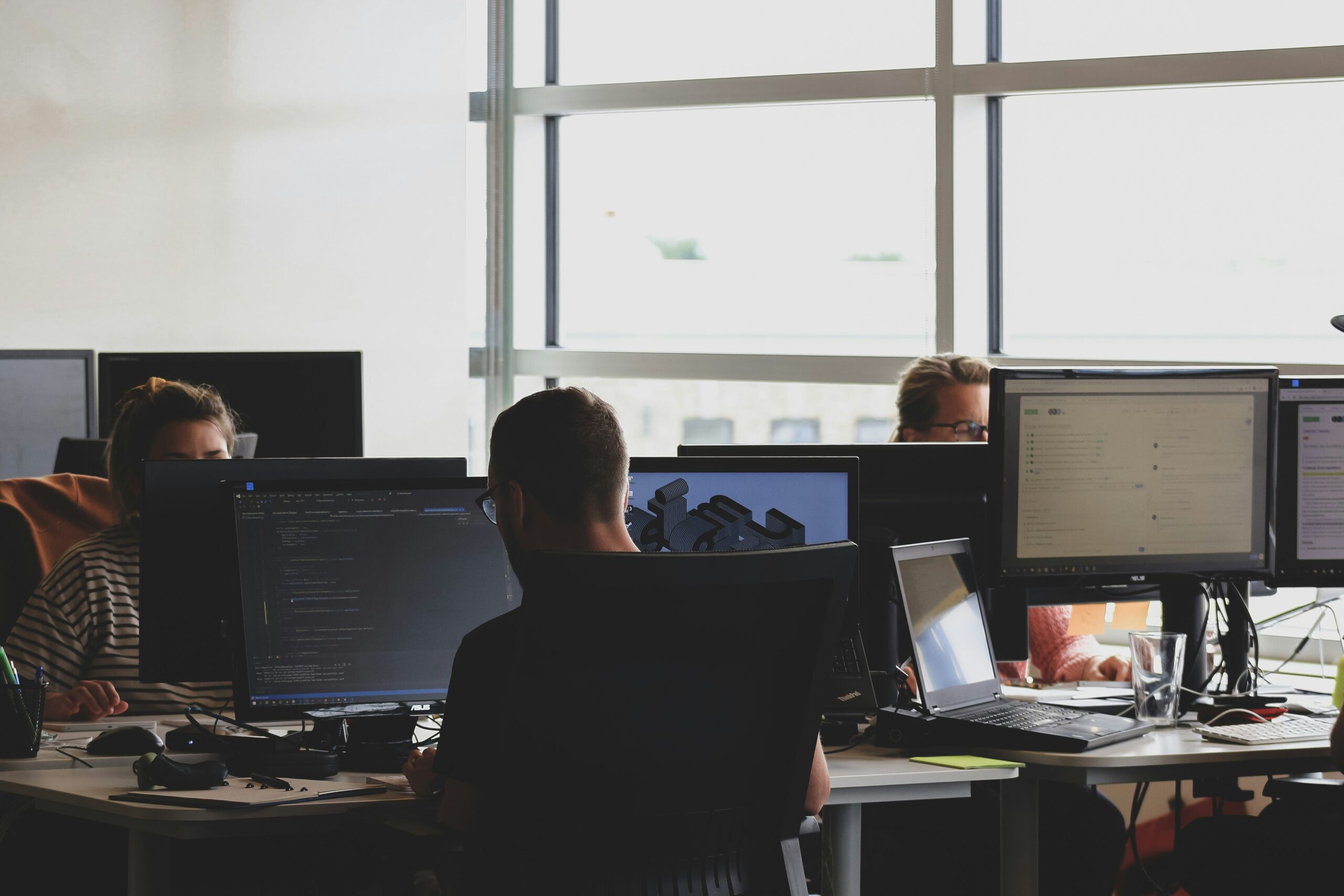 A team working on multiple screens in an office, analyzing AI-driven marketing data and analytics.