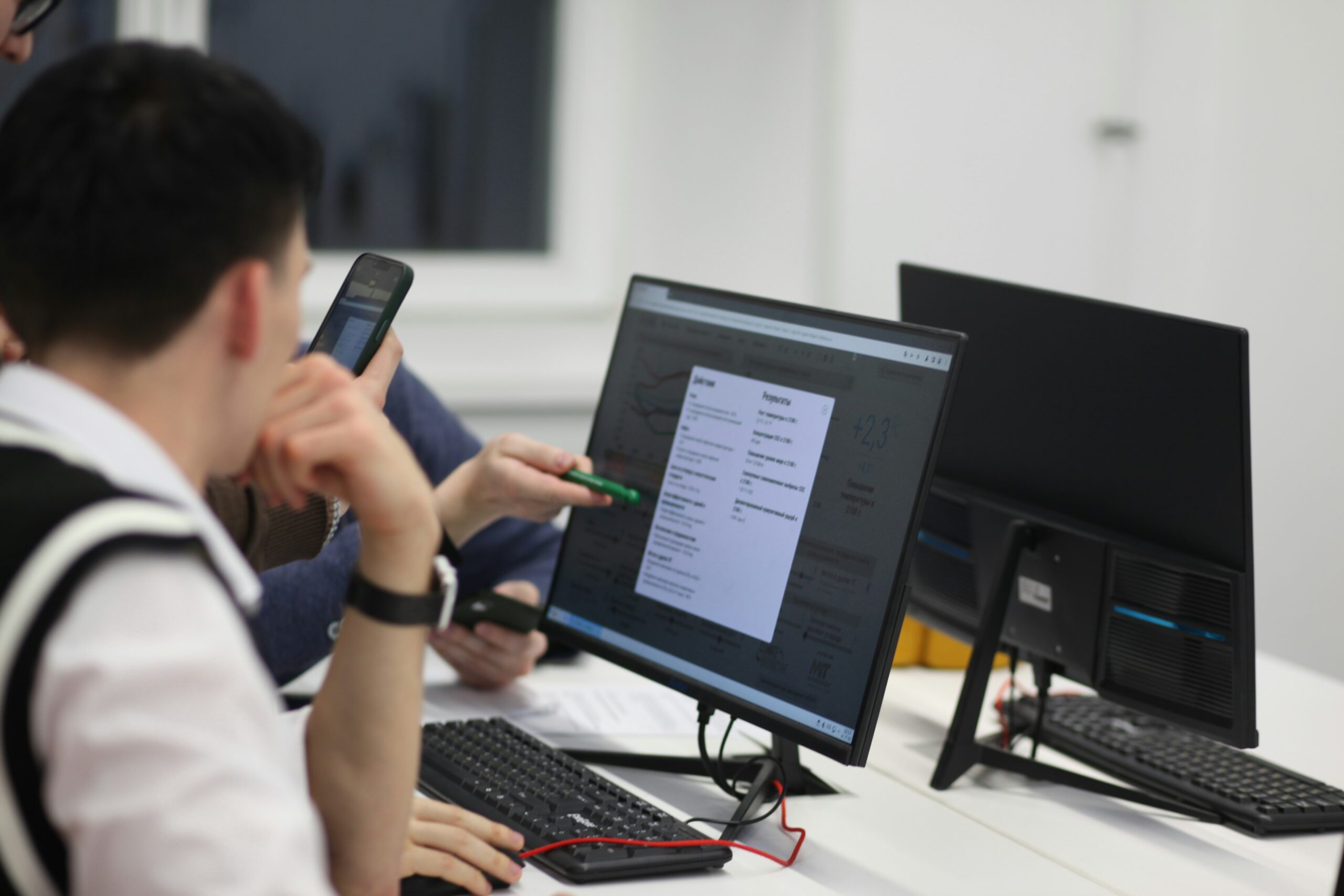 A group of professionals analyzing AI data on a desktop screen in an office setting