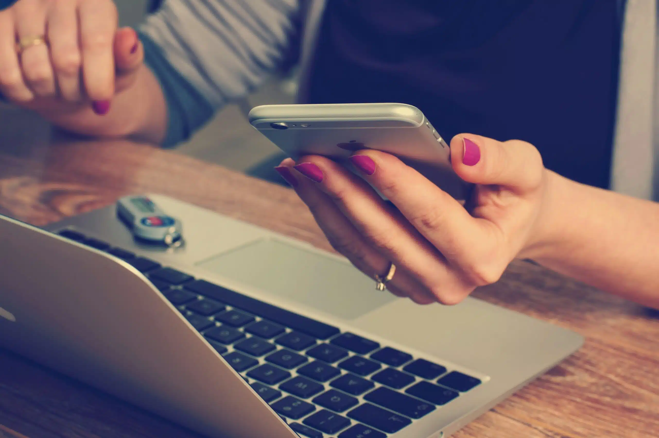 a woman looking at her phone with a laptop open