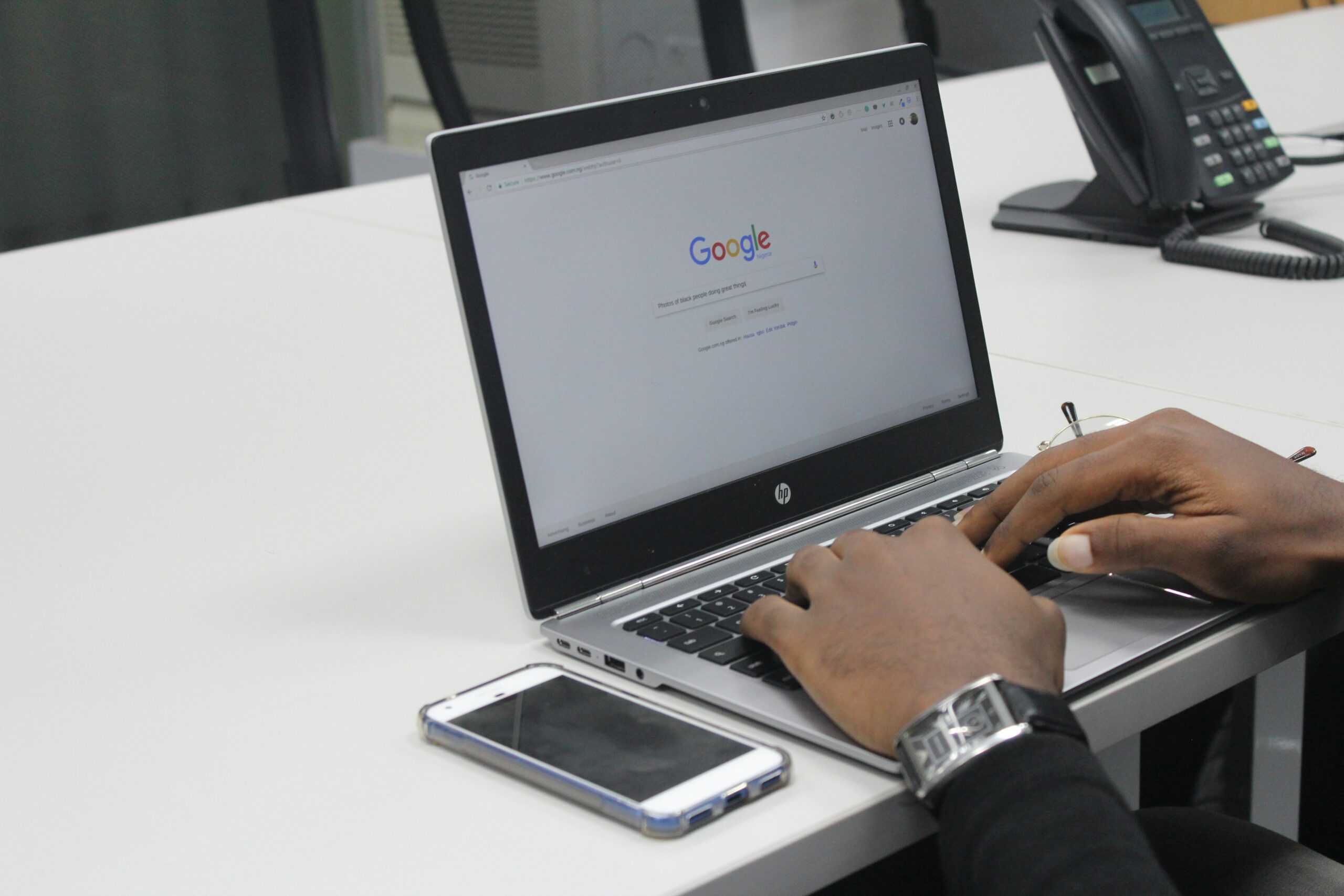 Hands typing on a laptop with Google search page open. - AI Marketing Tools Hands typing on a laptop with Google search page open.