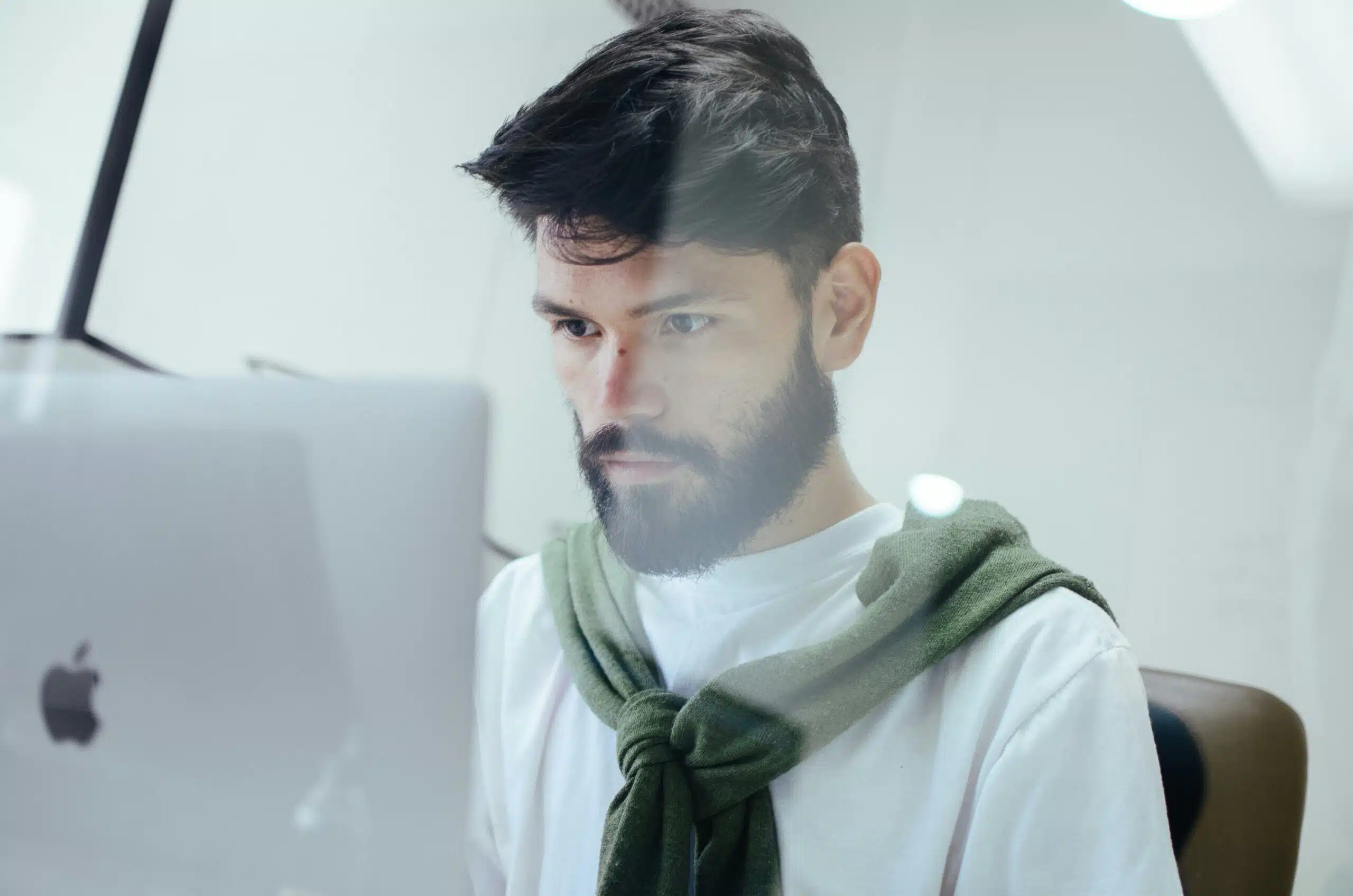 Man working on a MacBook in a bright office, understanding how ai image generation works.