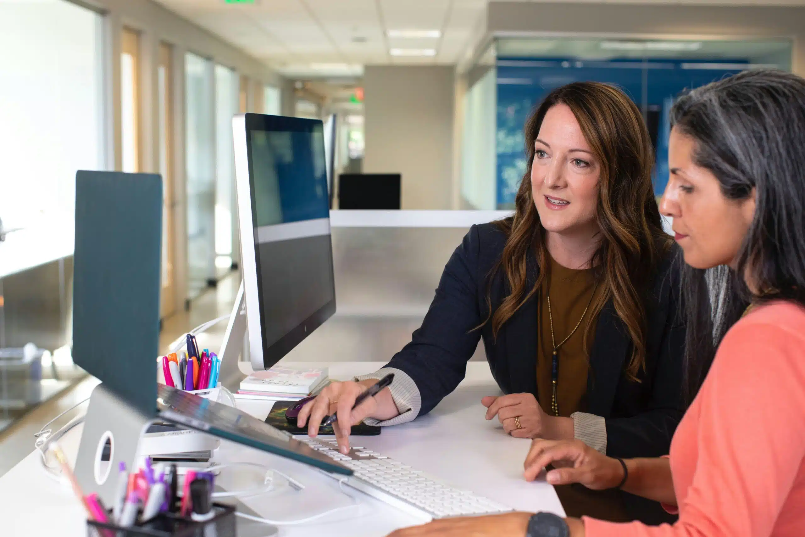 2 woman discussing in front of a computer