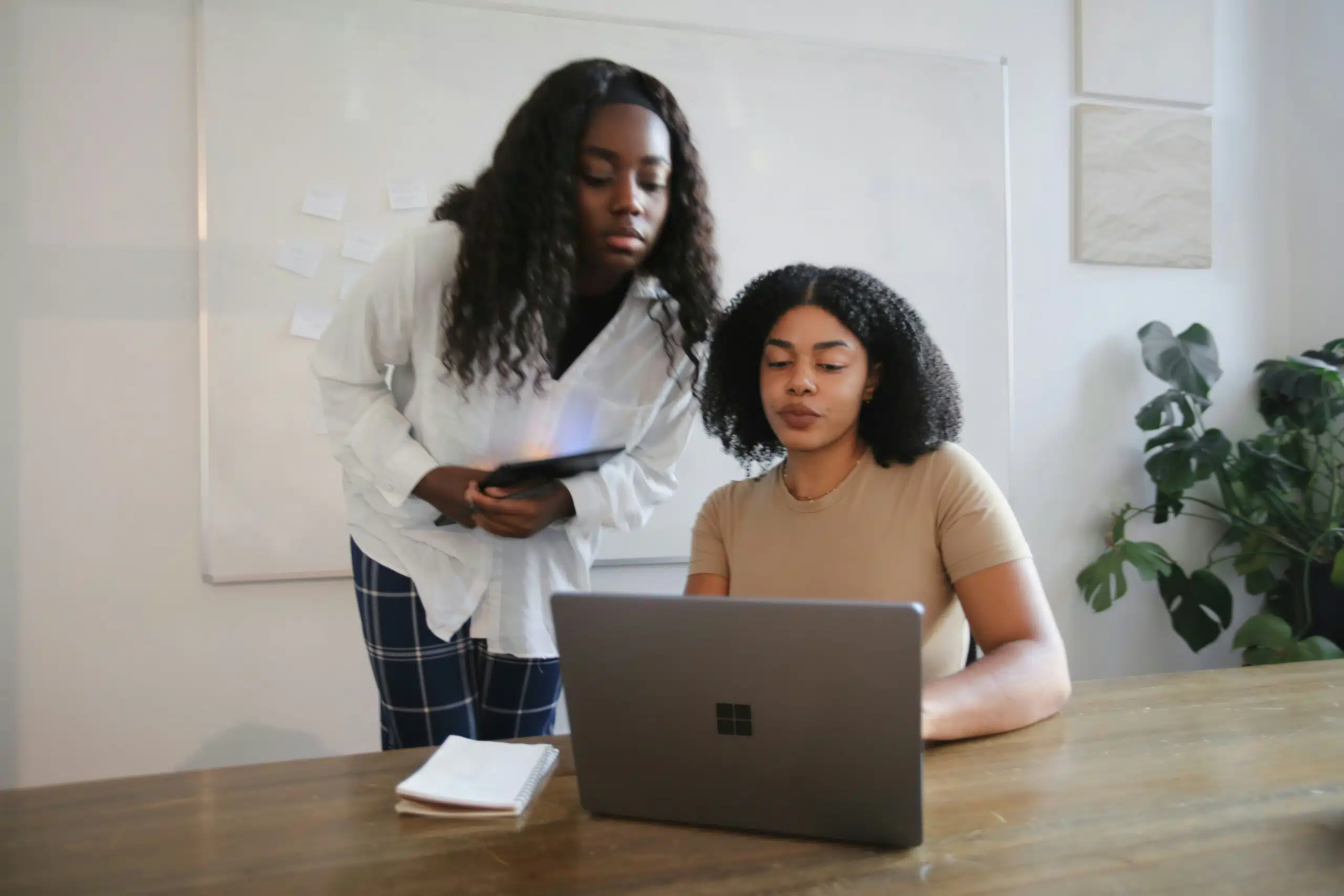 Two women working together on a laptop, reviewing automated advertising strategies 