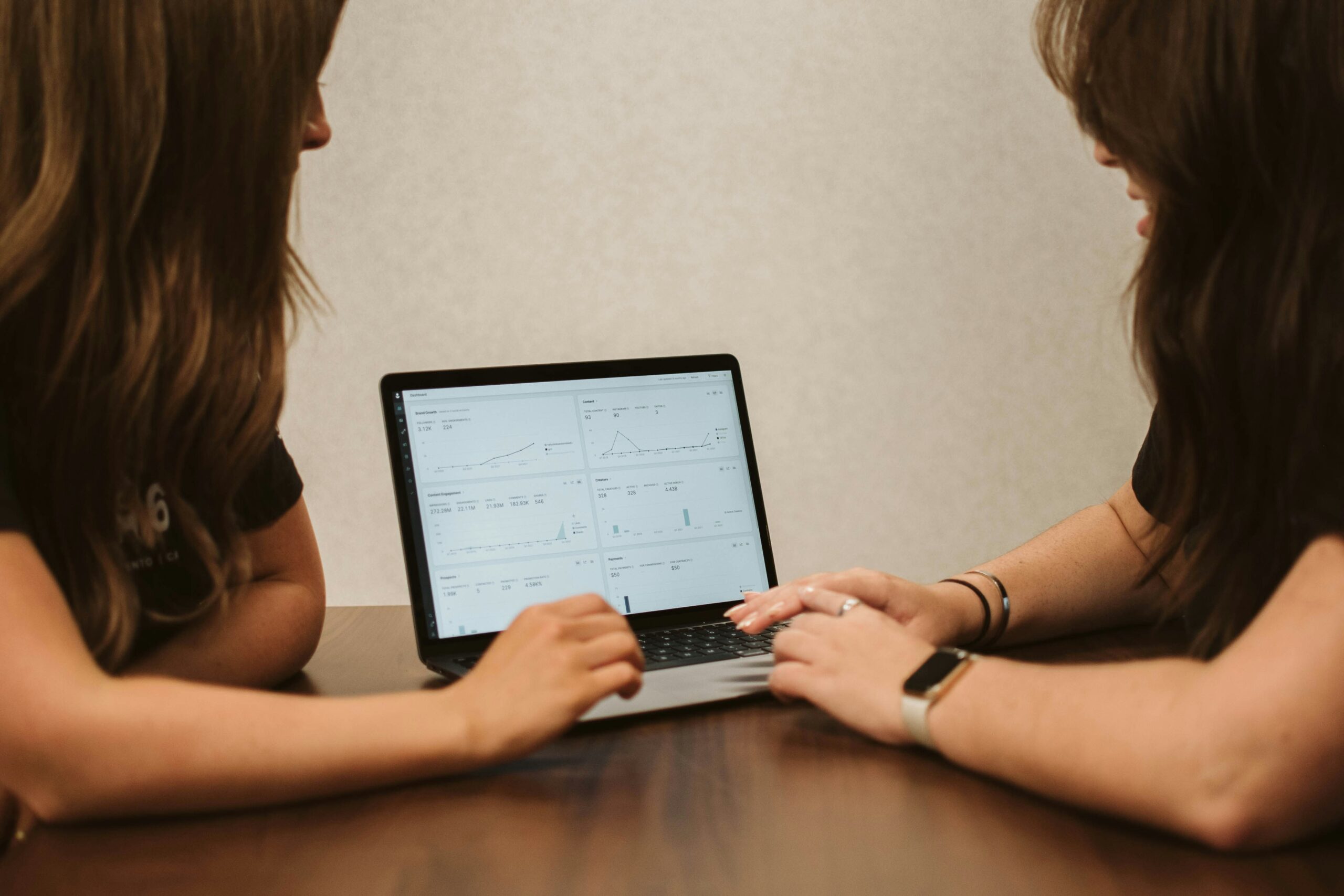 Two marketers reviewing performance metrics on a laptop, leveraging real-time data analysis for informed decision-making.