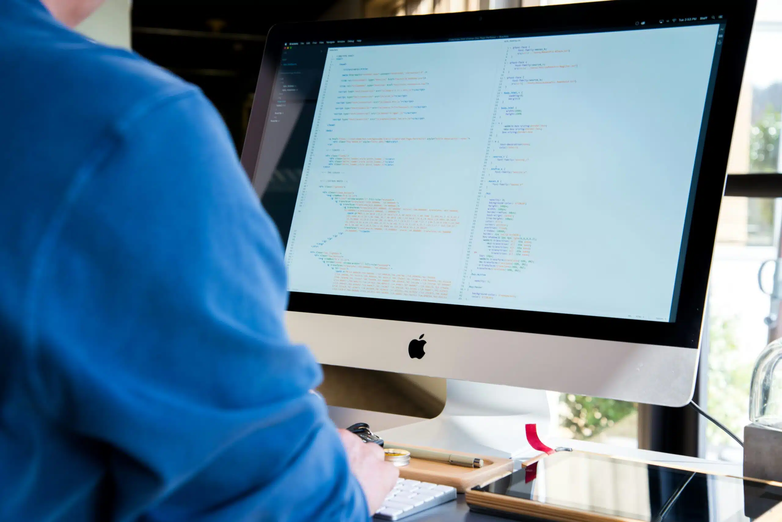 Person working on code at a large iMac screen