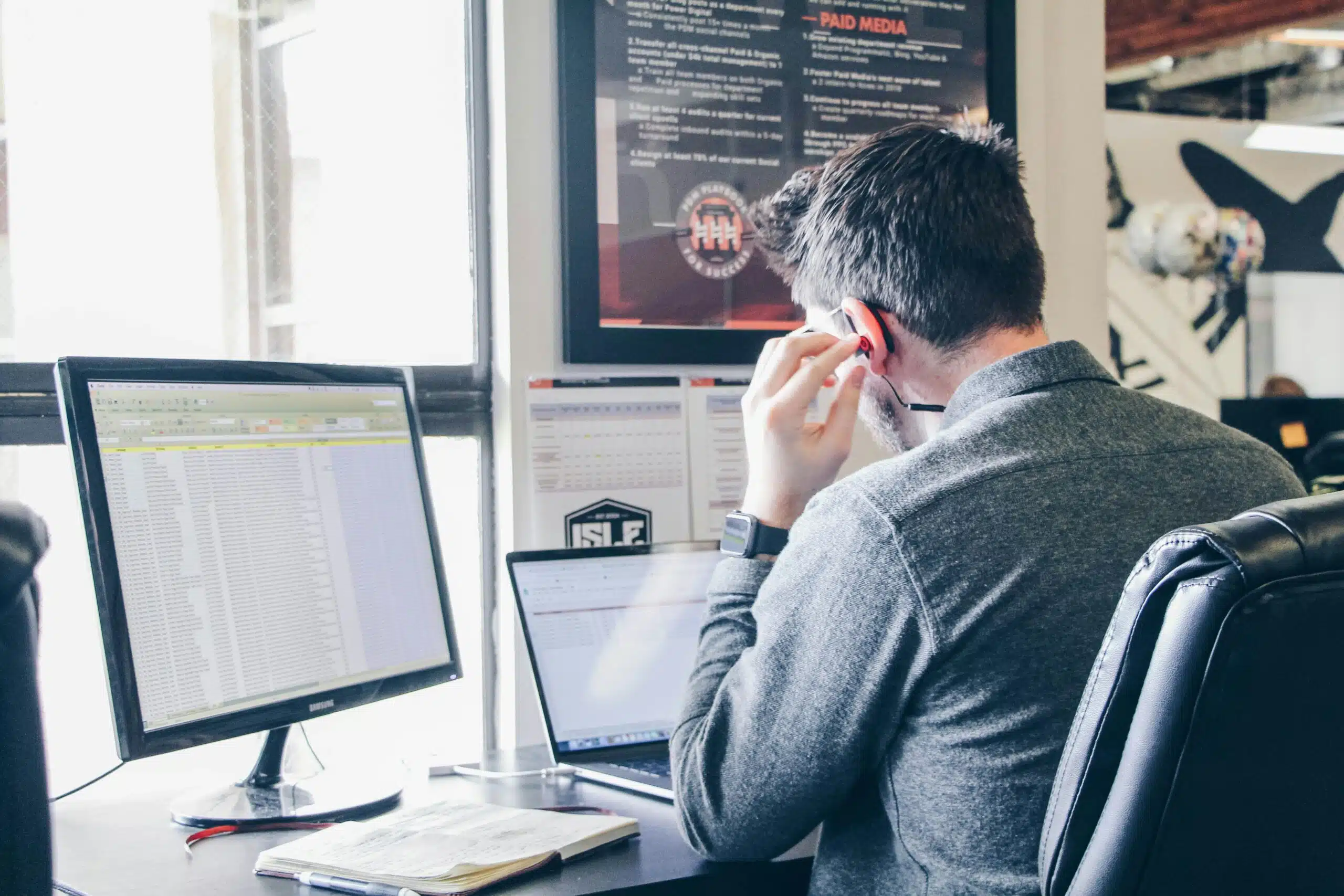 a professional working with a desktop and a laptop infront of him
