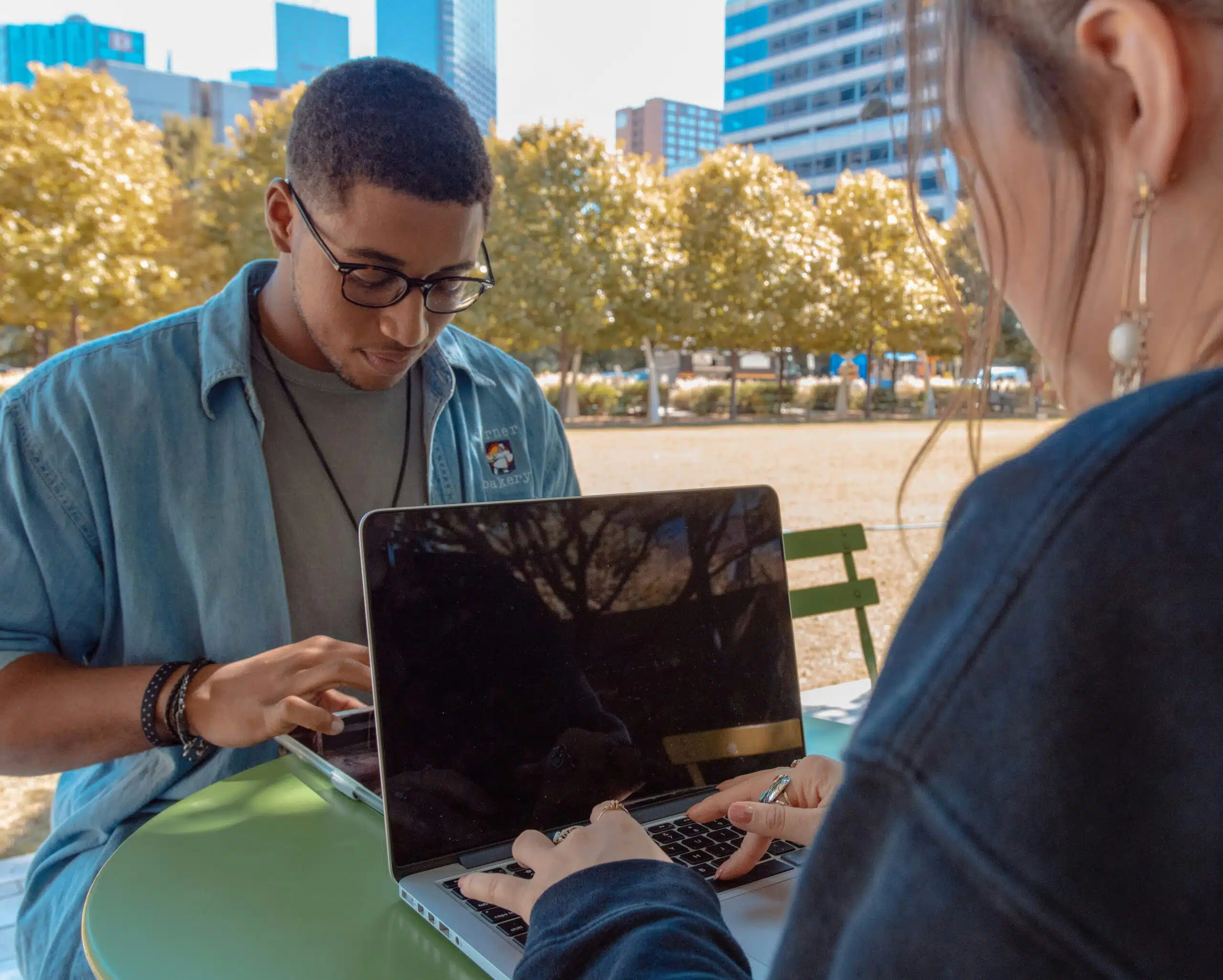 two people working outdoors on laptop