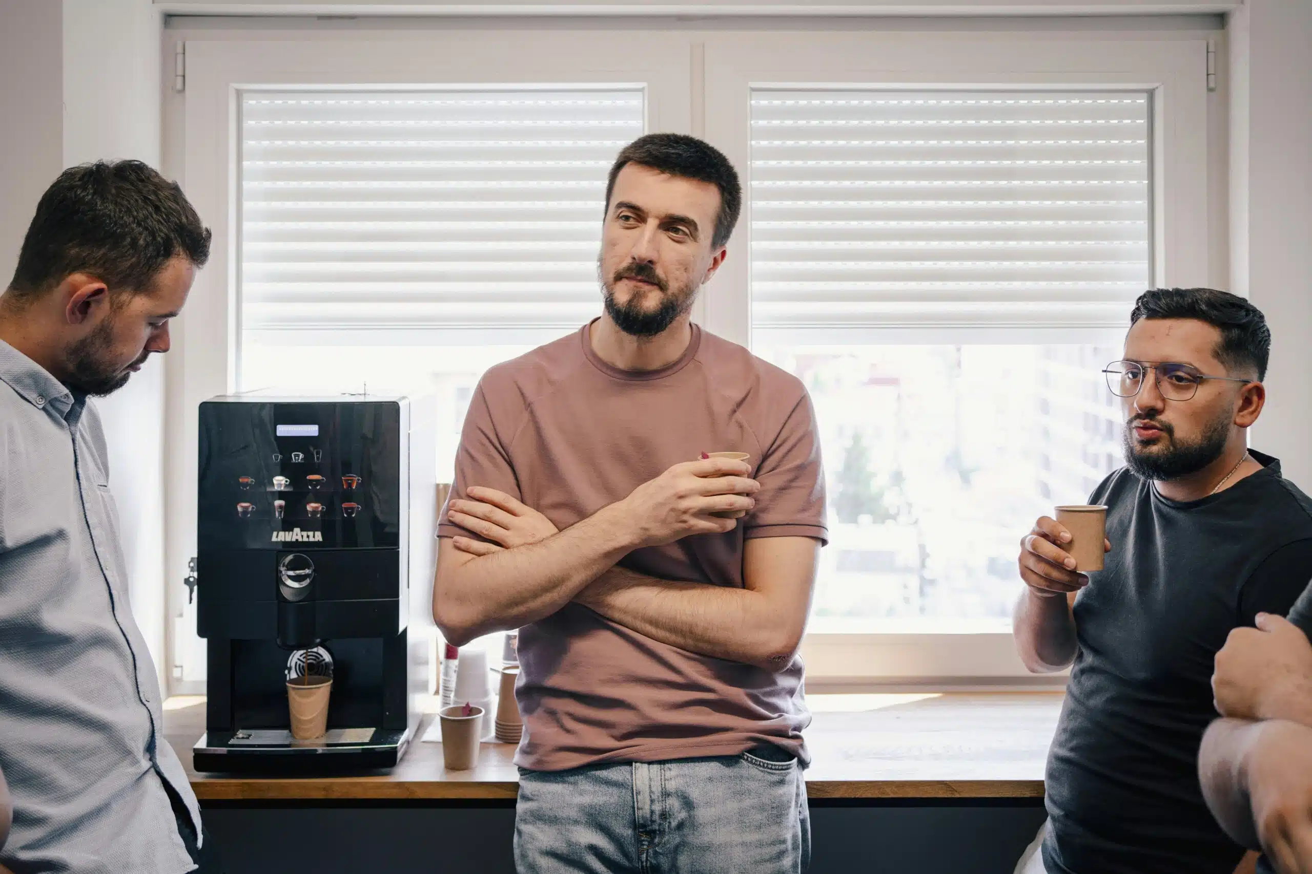 a team of 3 men discussing in an office break room