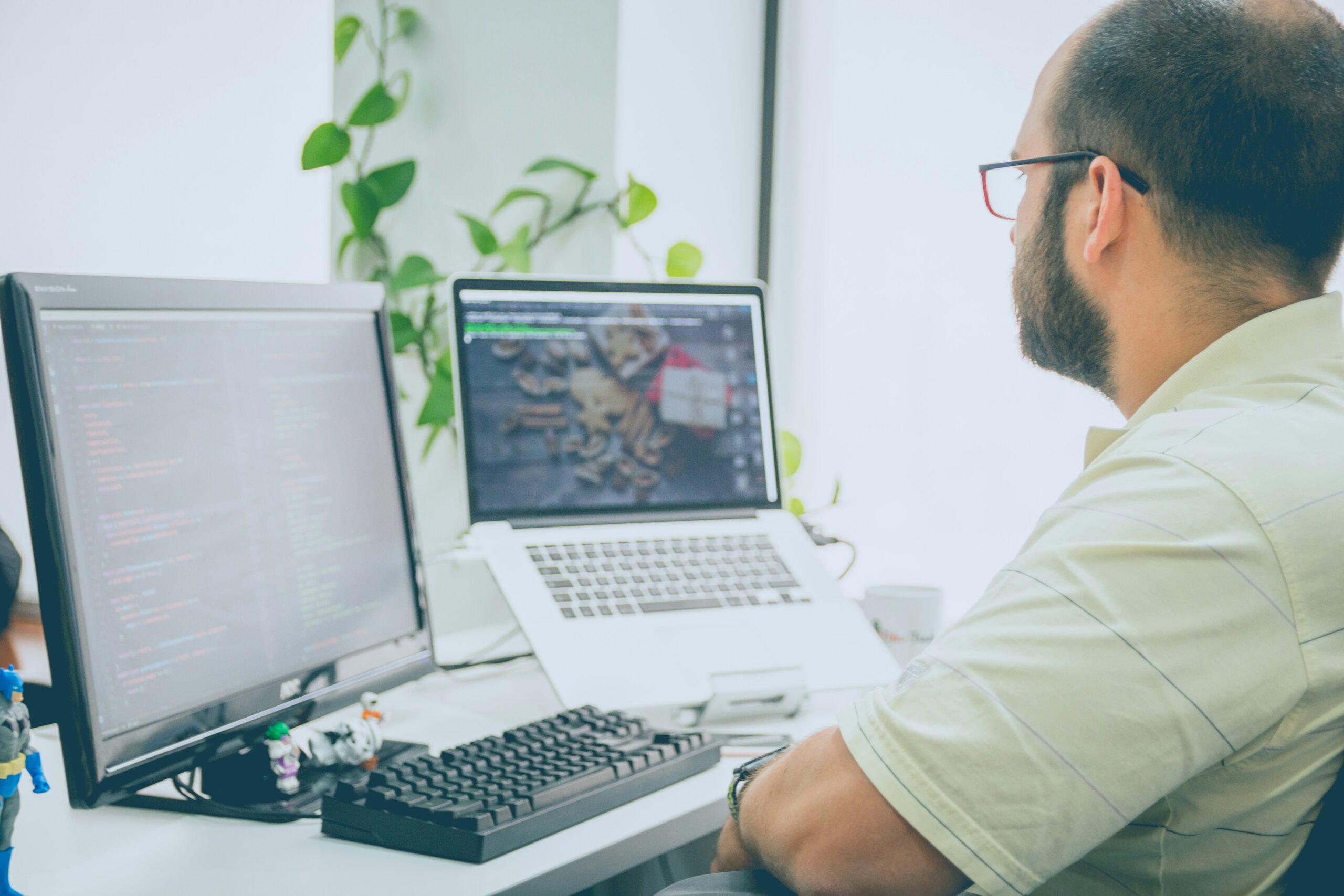 Developer working at a dual-monitor setup with code and design interface visible. - AI Marketing Tools Developer working at a dual-monitor setup with code and design interface visible.
