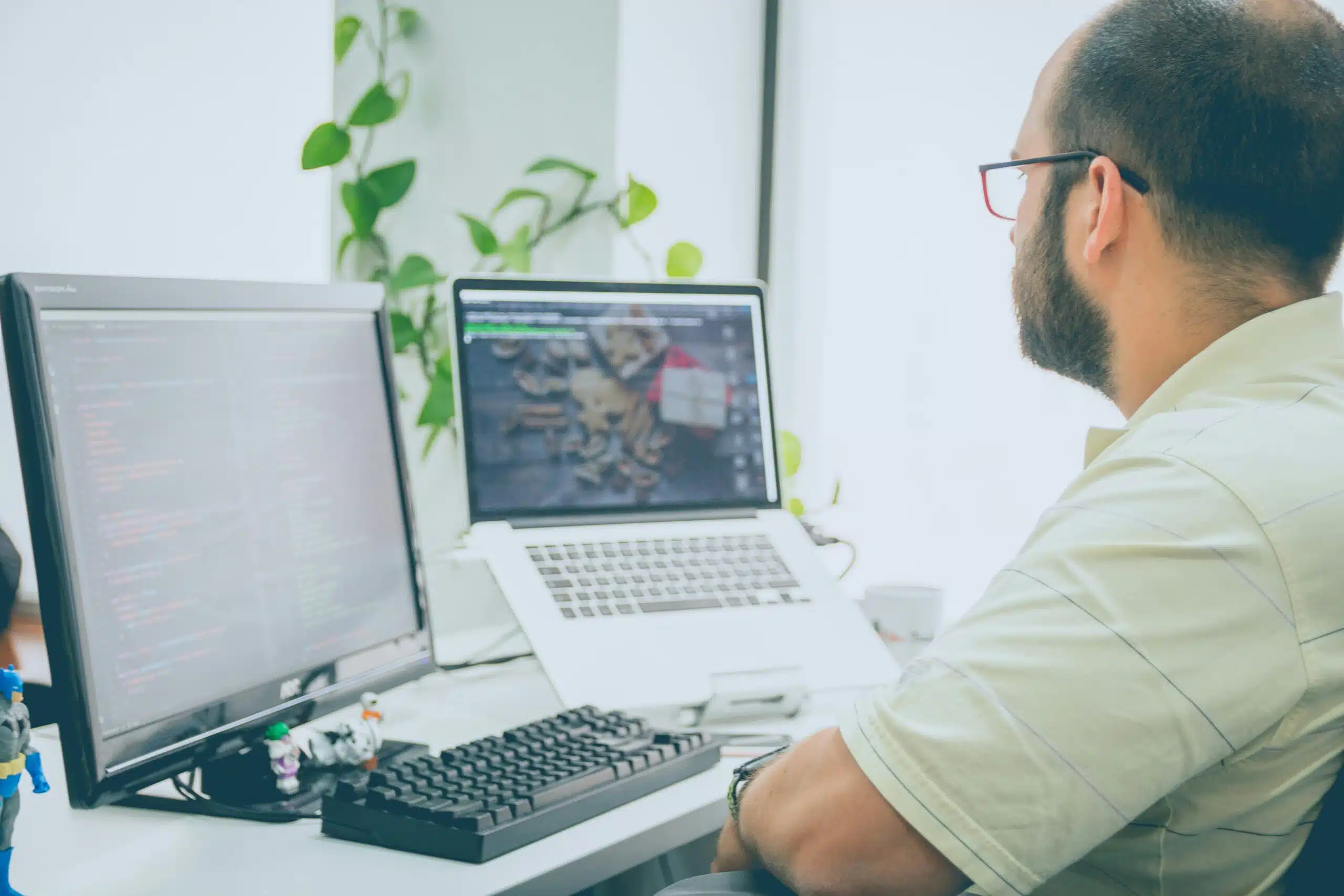 Developer working at a dual-monitor setup with code and design interface visible.