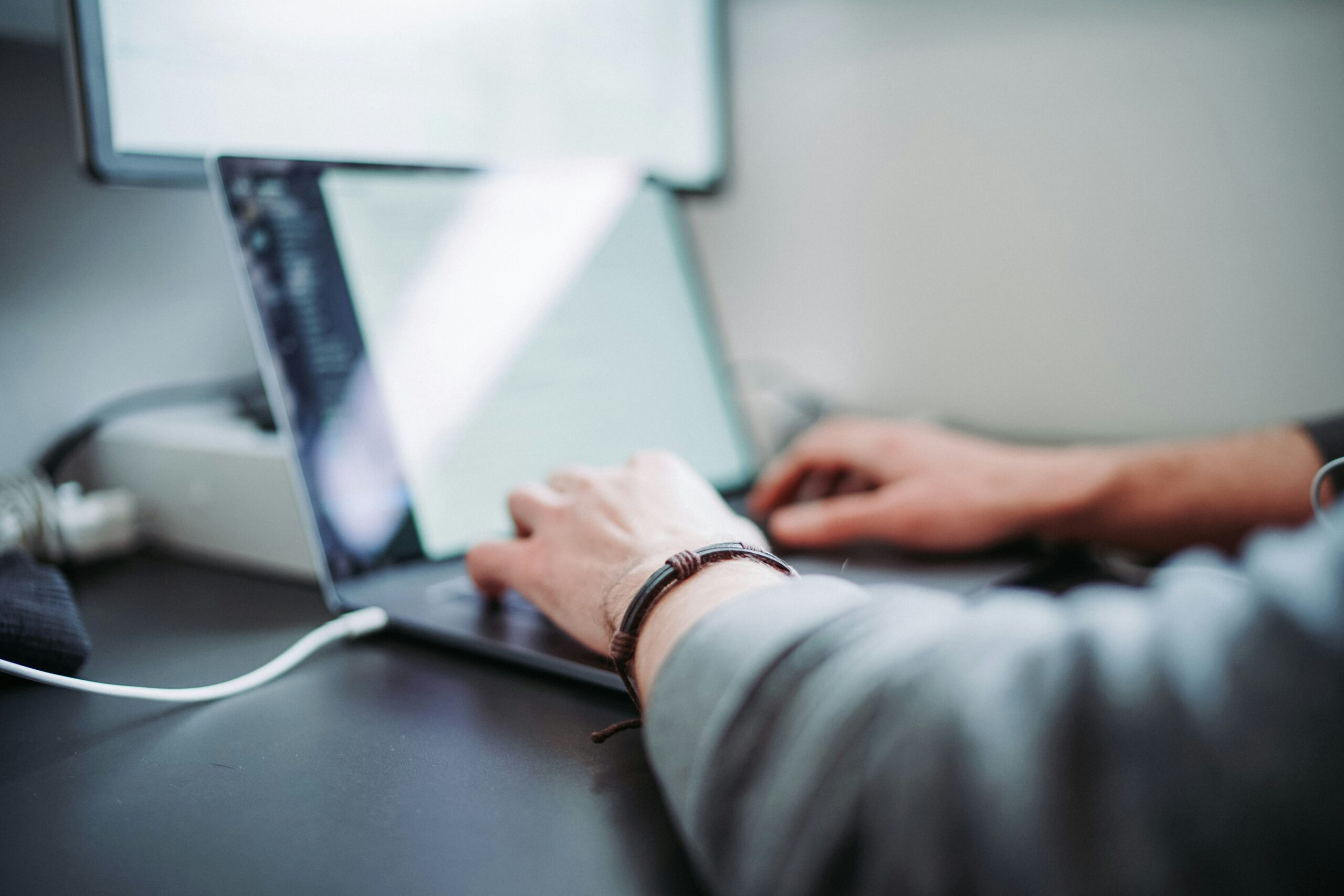 Blurred close-up of hands typing on a laptop connected to a secondary screen, representing hands-on AI implementation. - AI Marketing Tools Blurred close-up of hands typing on a laptop connected to a secondary screen, representing hands-on AI implementation.