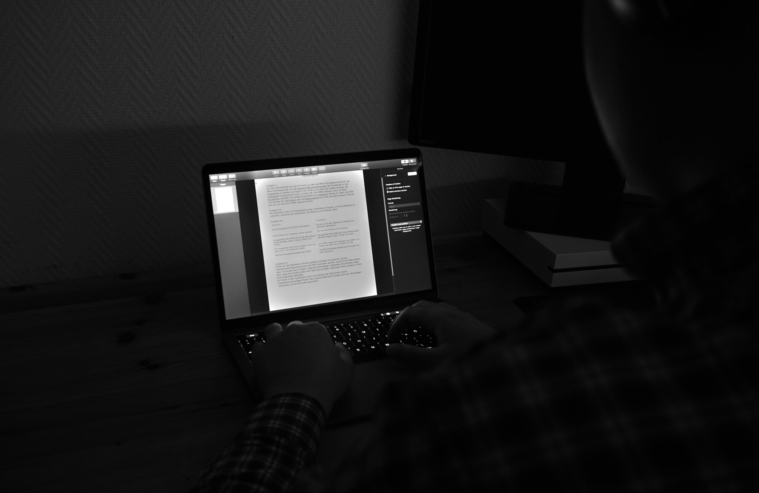  Person editing a text document on a laptop in a dimly lit room.