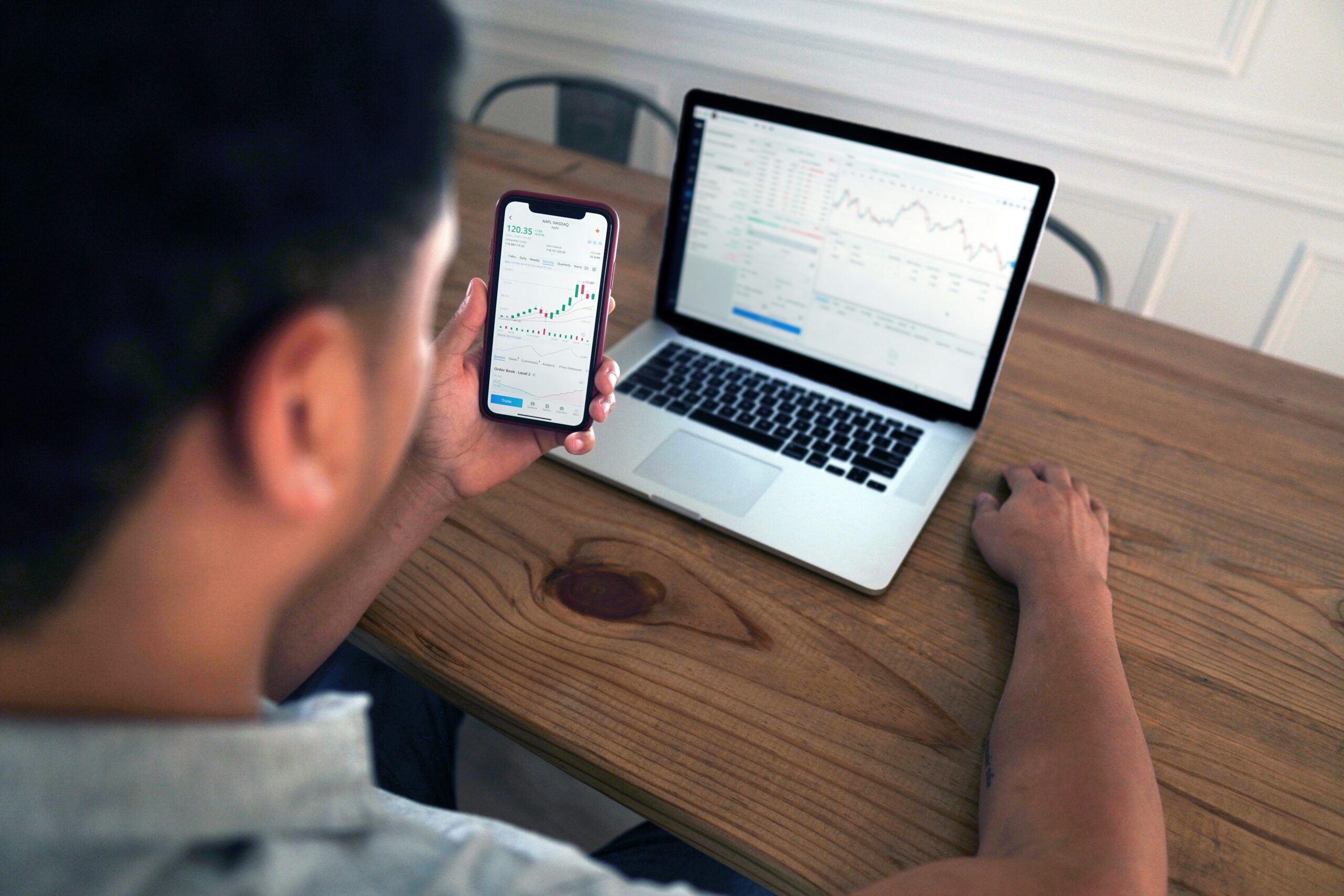Man examining predictive analytics charts on a smartphone and laptop screen.