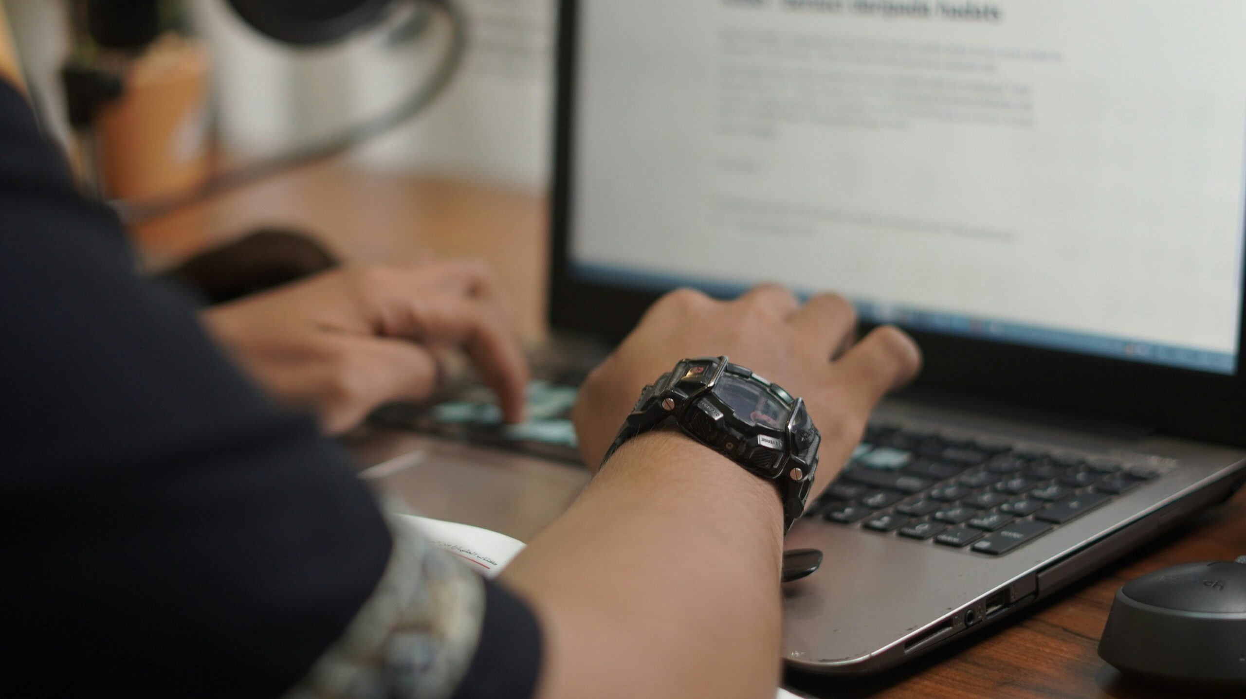 Close-up of hands typing on a laptop with a document or analytics tool open. - AI Marketing Tools Close-up of hands typing on a laptop with a document or analytics tool open.