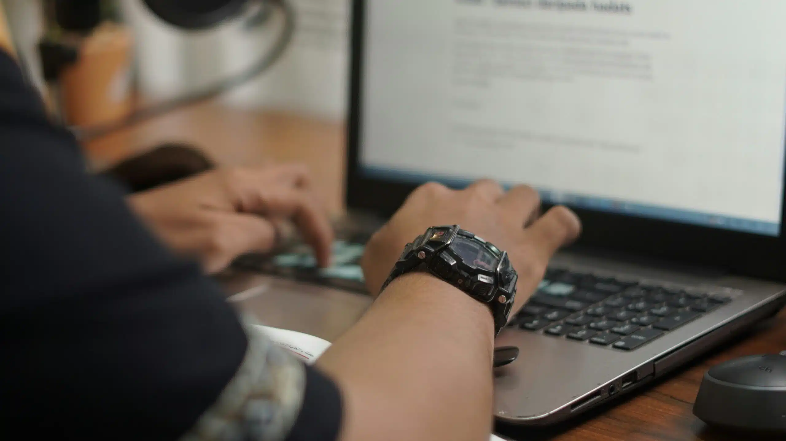 Close-up of hands typing on a laptop with a document or analytics tool open.