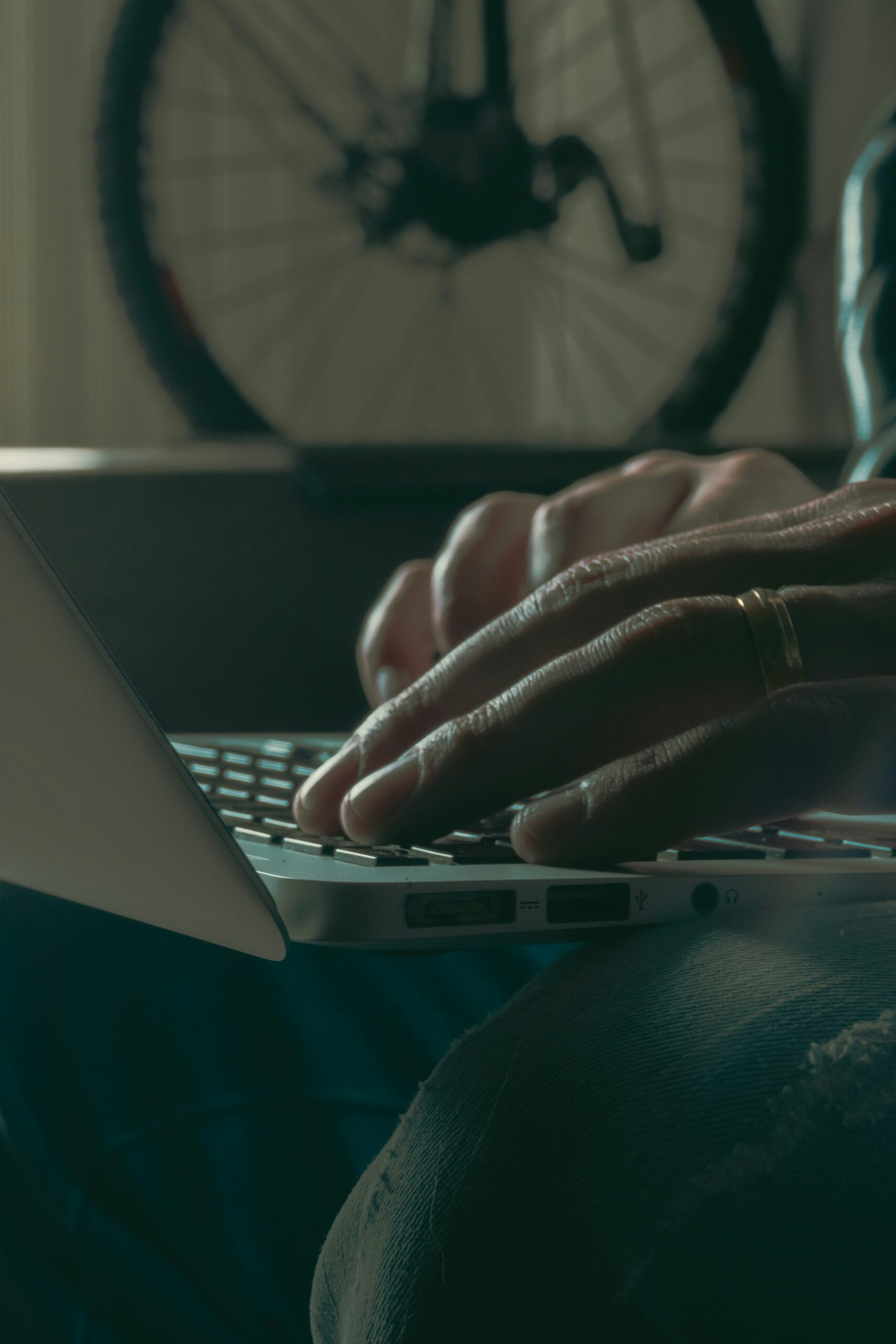Close-up of hands typing on a keyboard with a blurred bicycle in the background.